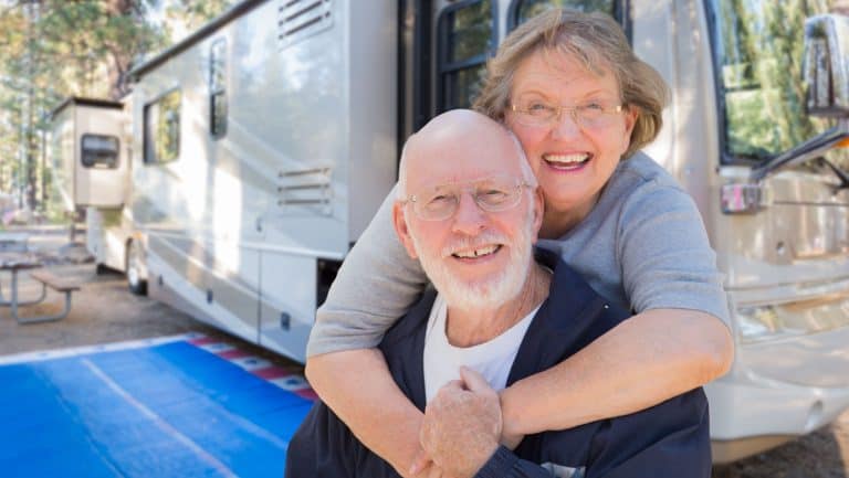 Senior Couple In Front of Their Beautiful RV At The Campground.
