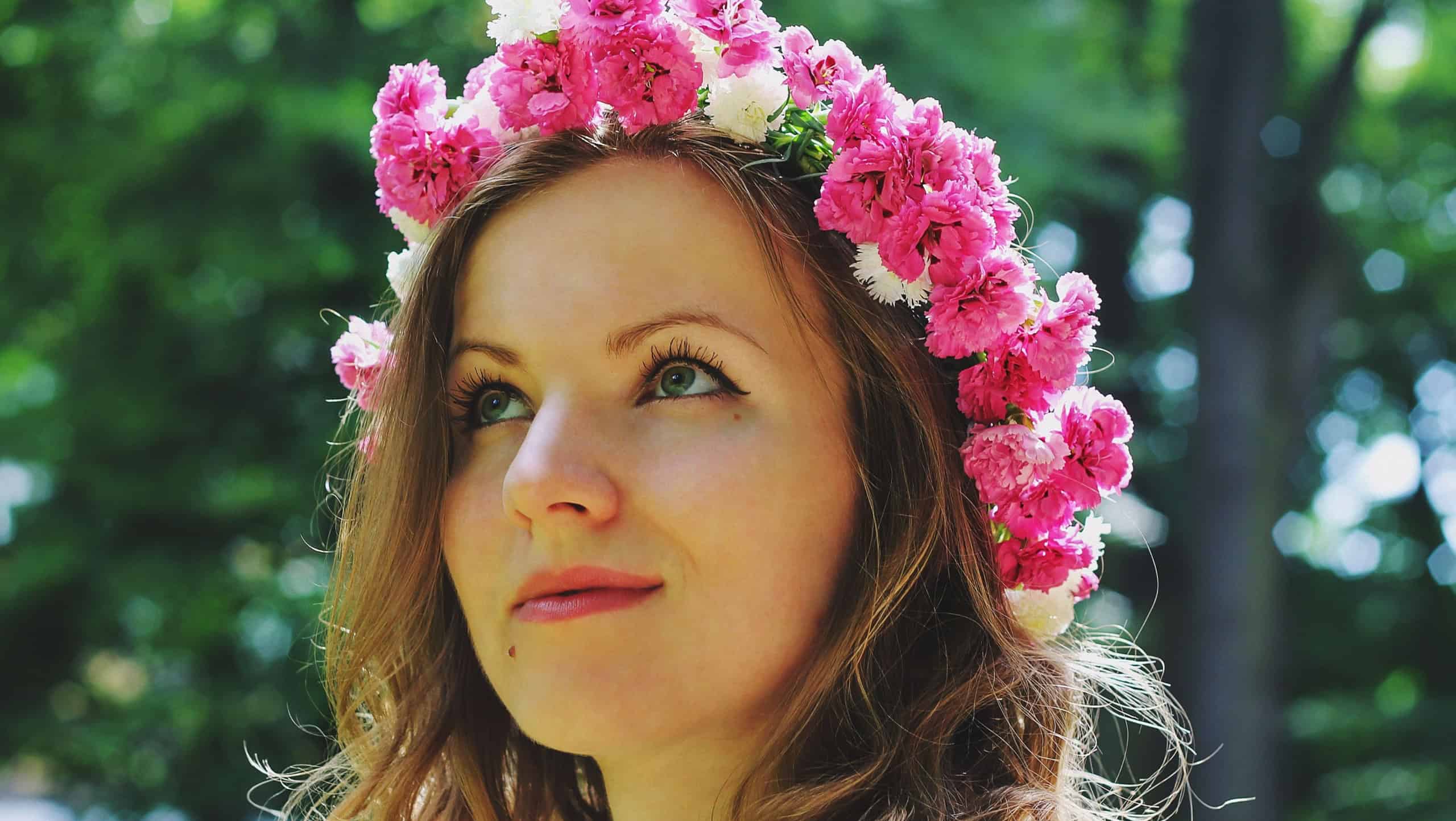 Beautiful girl in pink flower crown looks into distance in summer park. Spring woman photo. International women's day and mother's day holidays. Flower chaplet. Pure sight. In profile portrait.