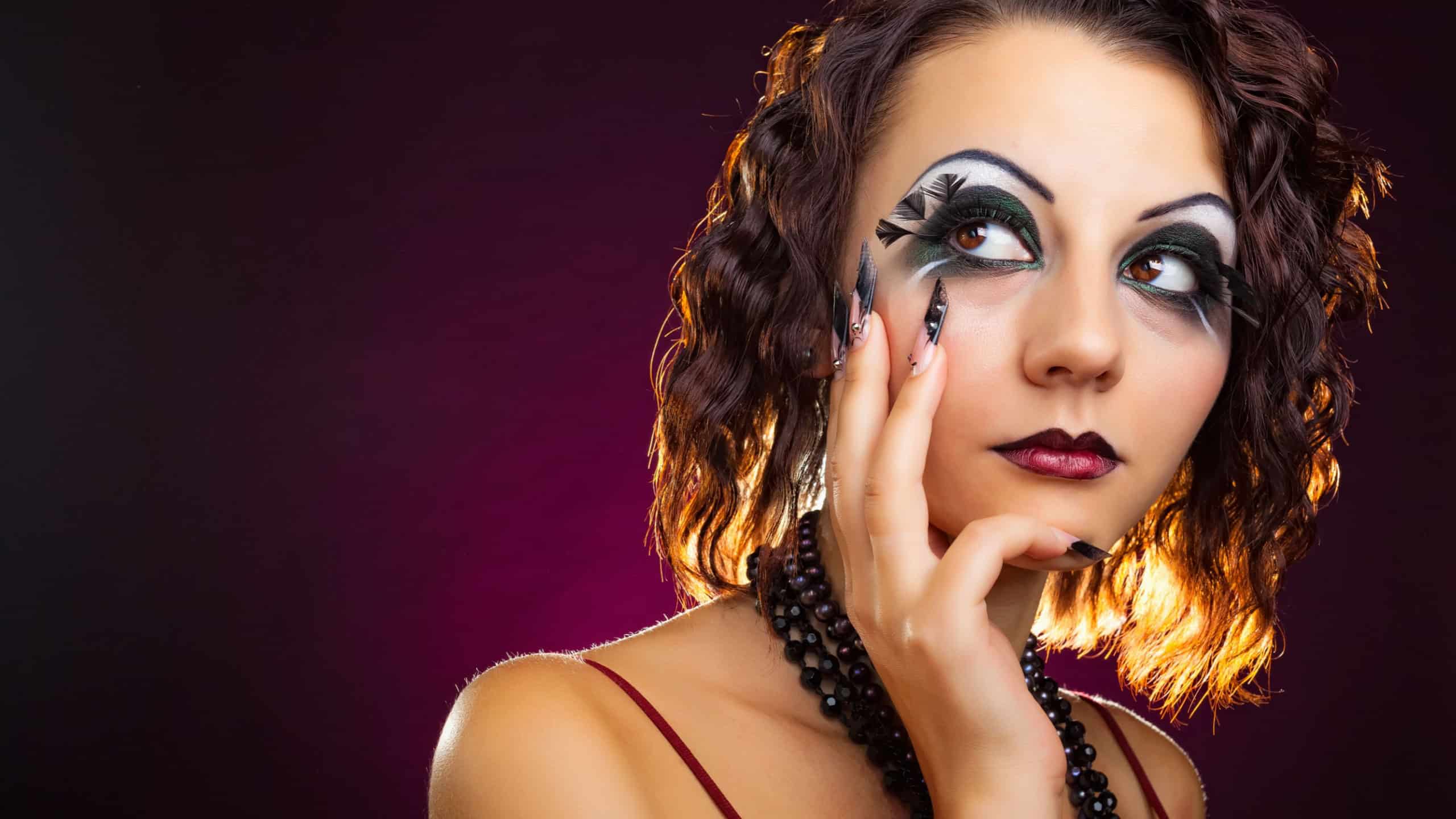 Close-up portrait of beautiful young woman model with retro glamour makeup and extravagant manicure on dark background