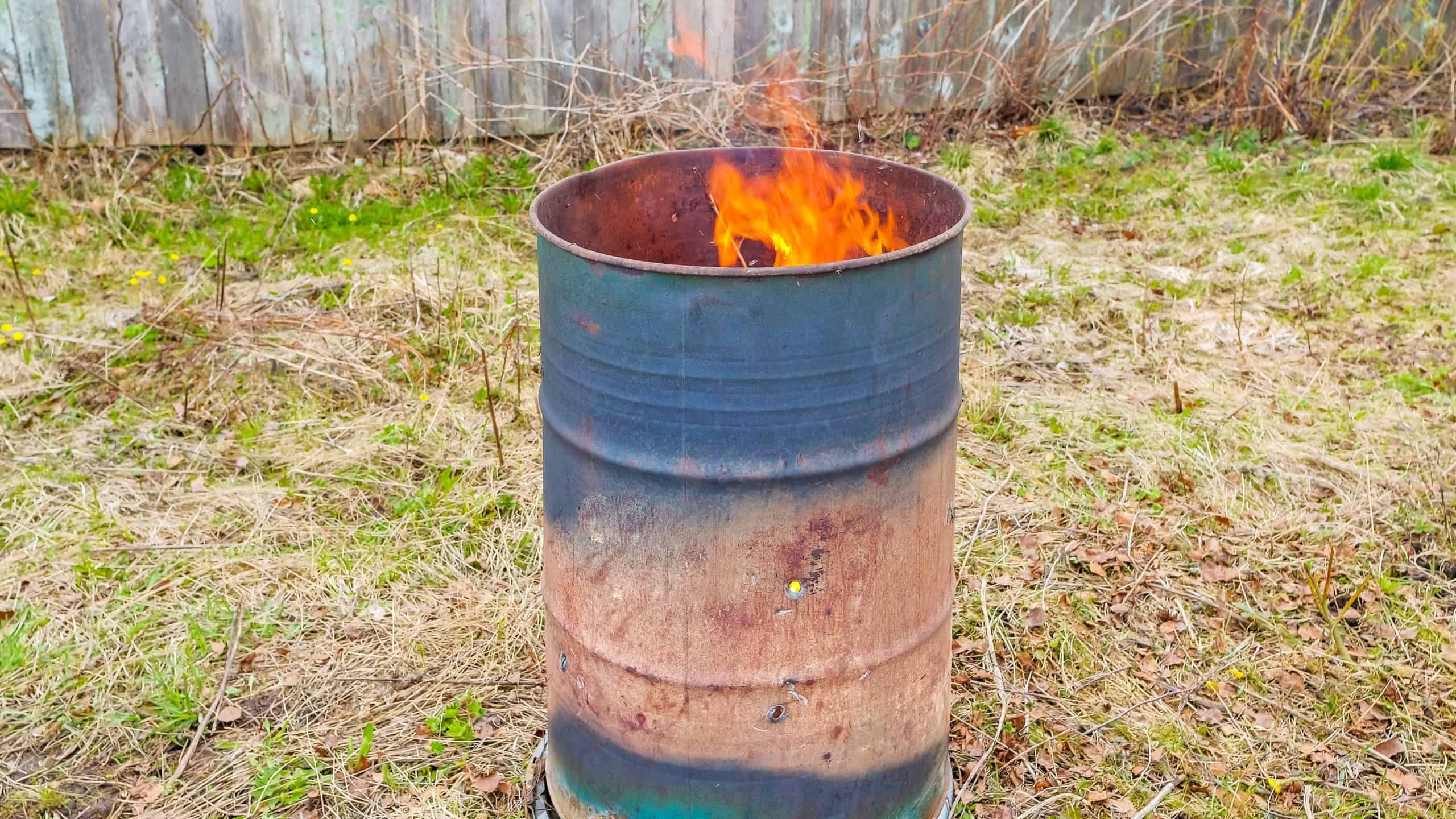Burning garbage in rusty iron barrel on the countryside area
