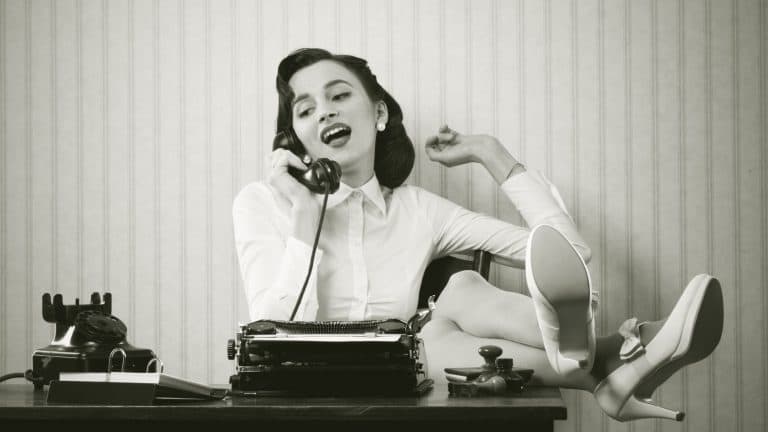Business woman puts her feet up on her desk on the phone
