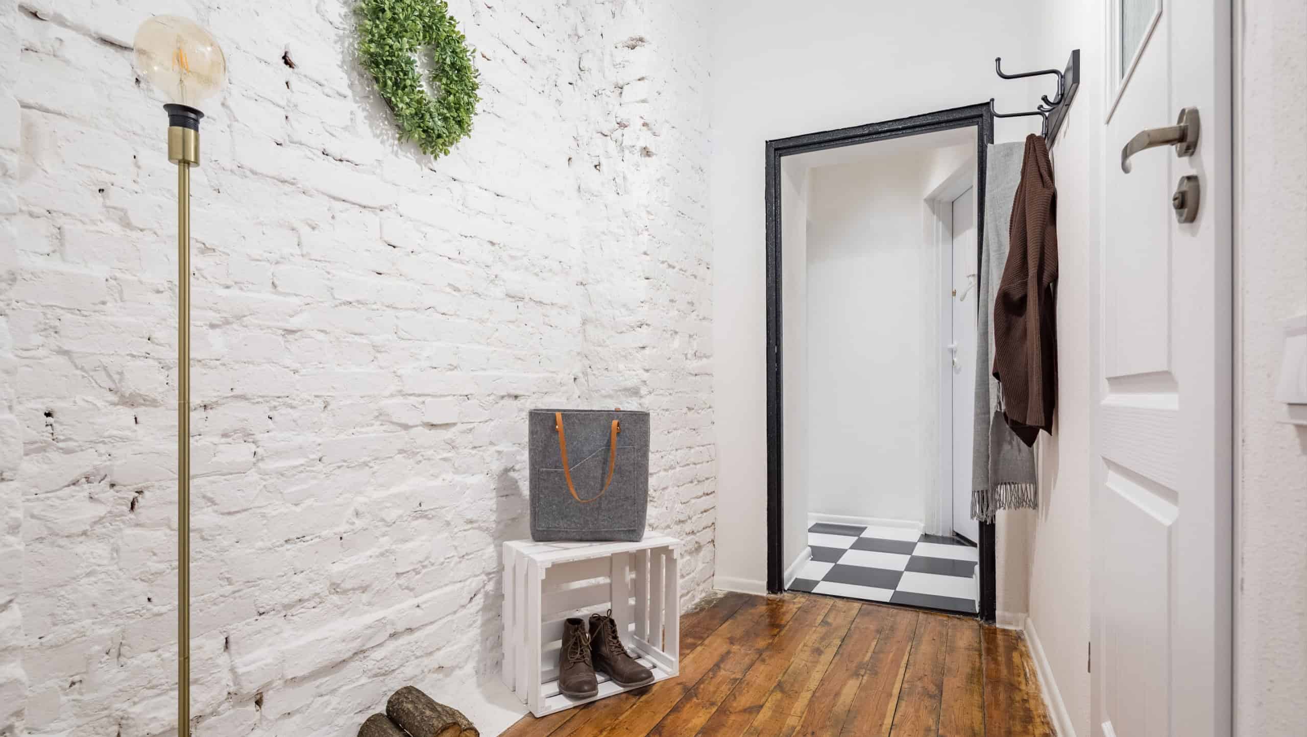 Industrial style mudroom with white brick wall and rustic hardwood flooring