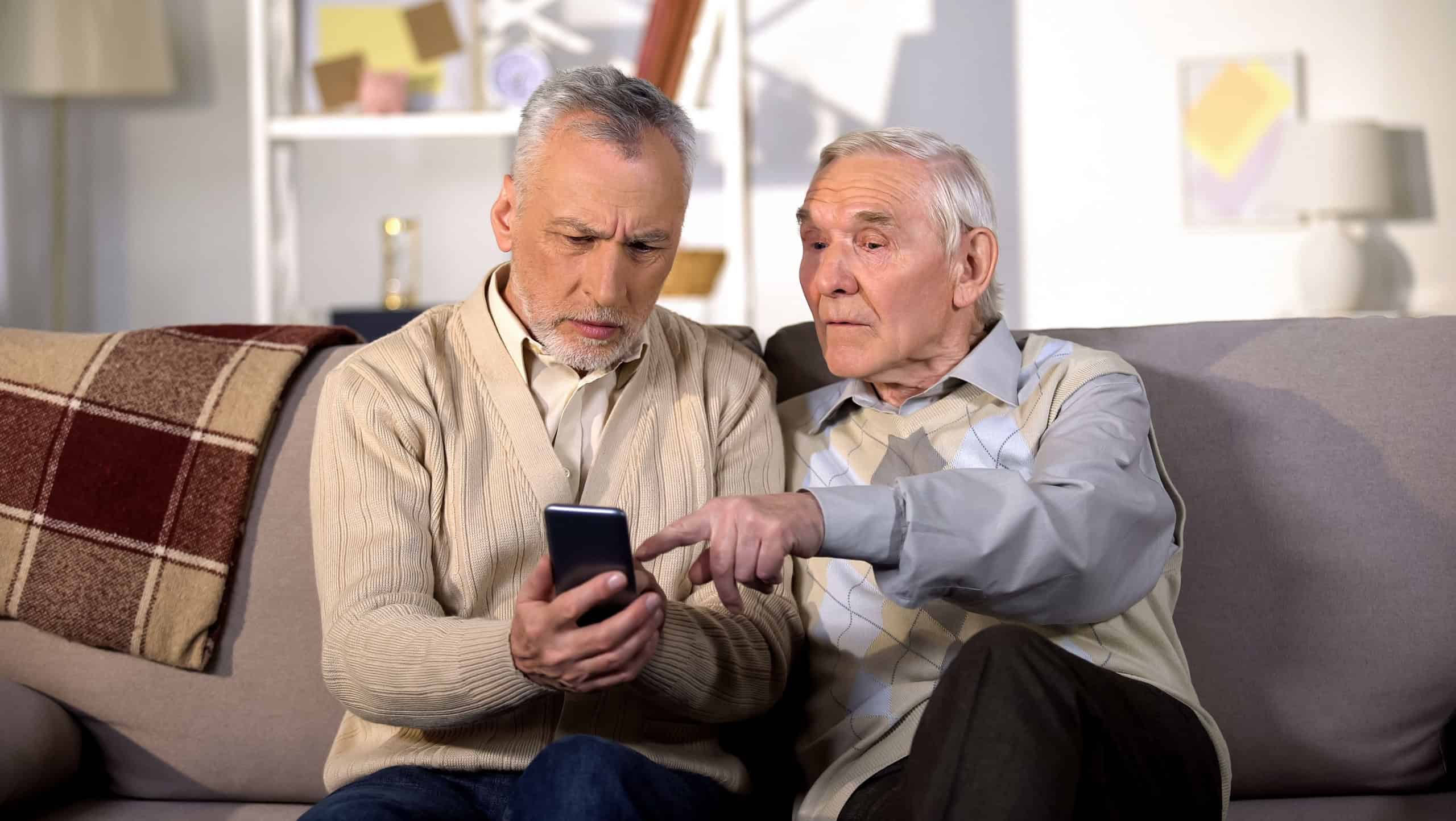 Two mature friends learning to use smartphone application, modern technology