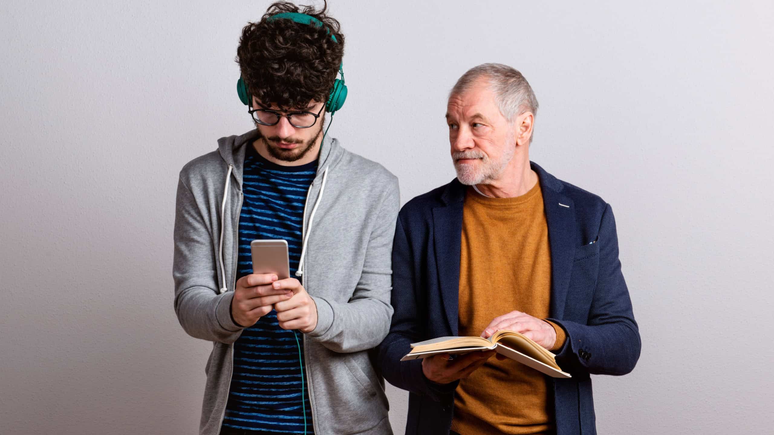Studio shot of young versus old generation, technology addiction concept.