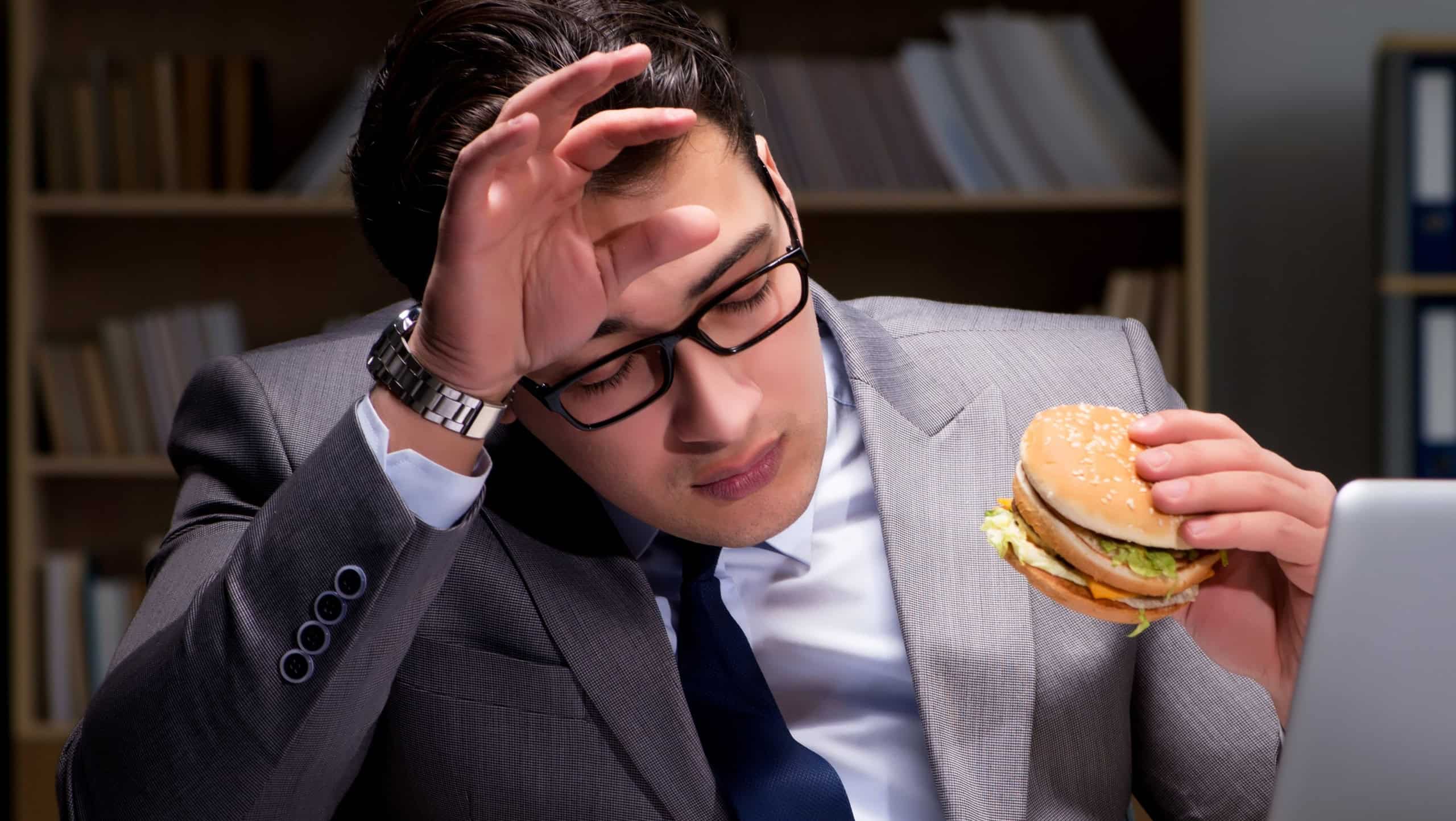 Businessman late at night eating a burger