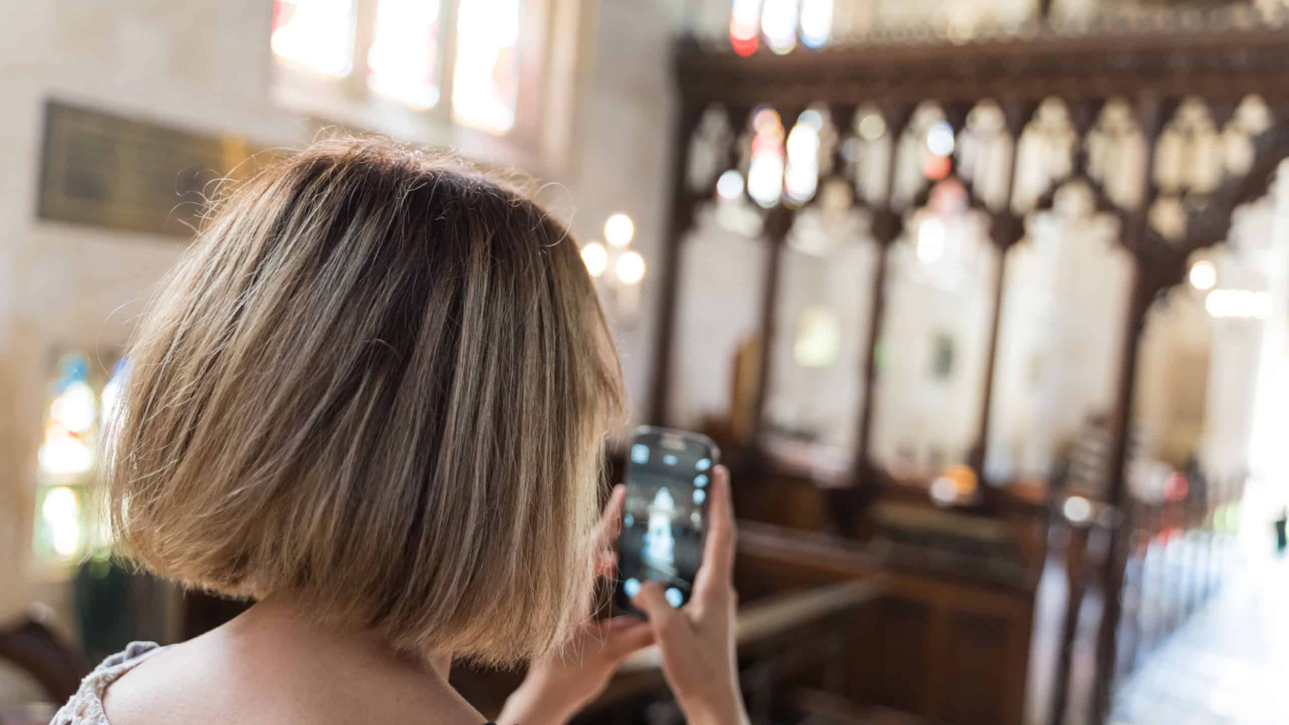 Stock photo of a young girl taking pictures with her cell phone in a church. Travel concept