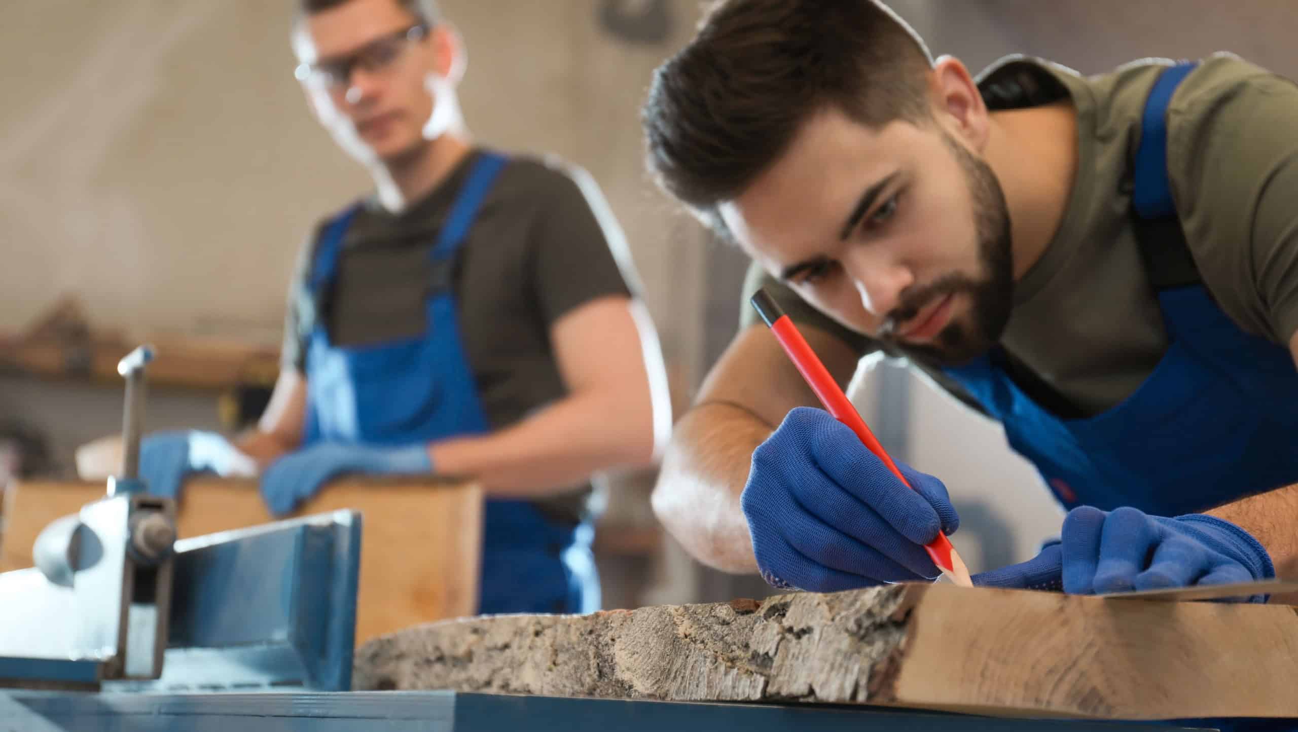 Professional carpenter making mark on wooden board in workshop