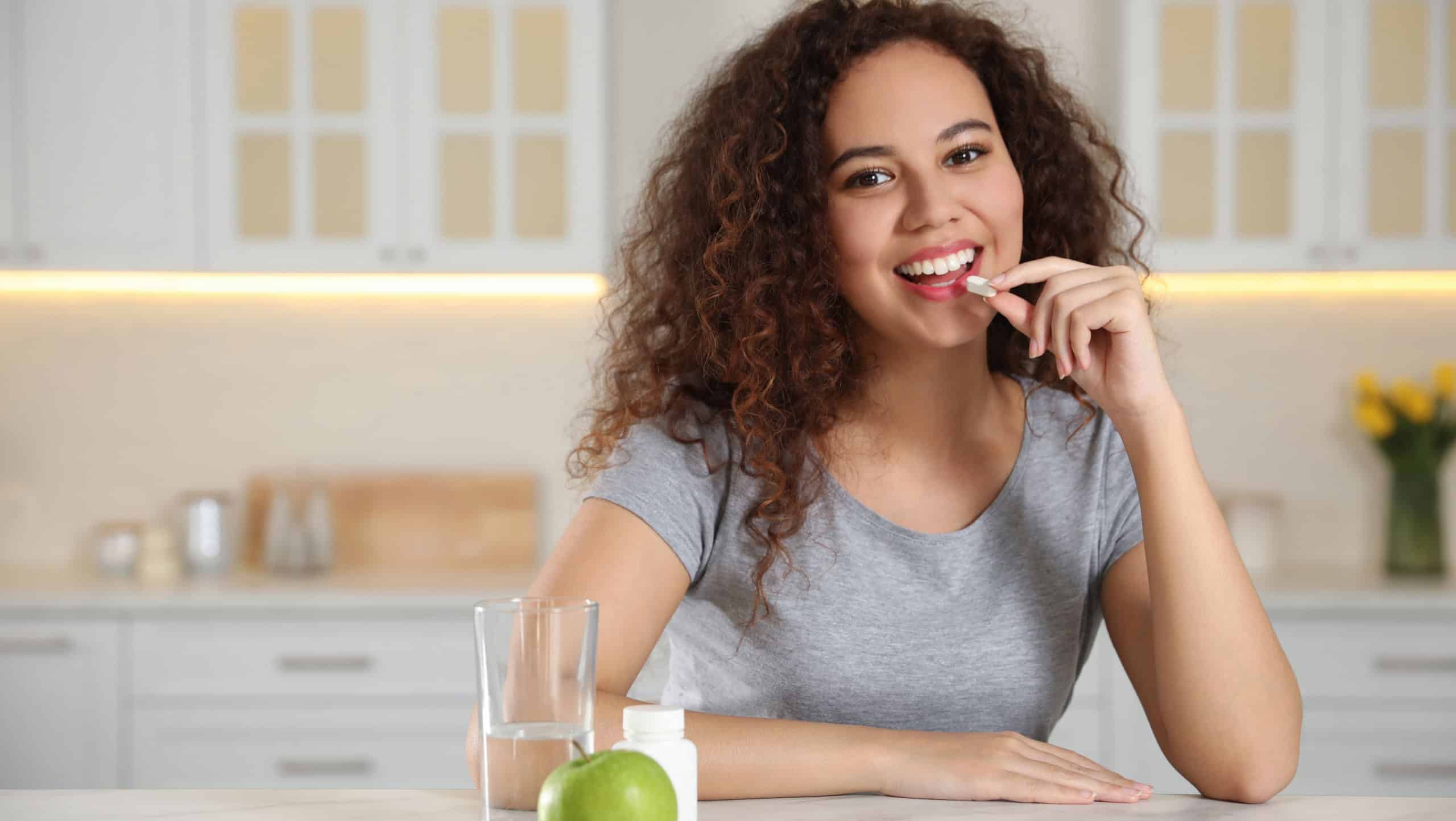 African-American woman taking vitamin pill in kitchen