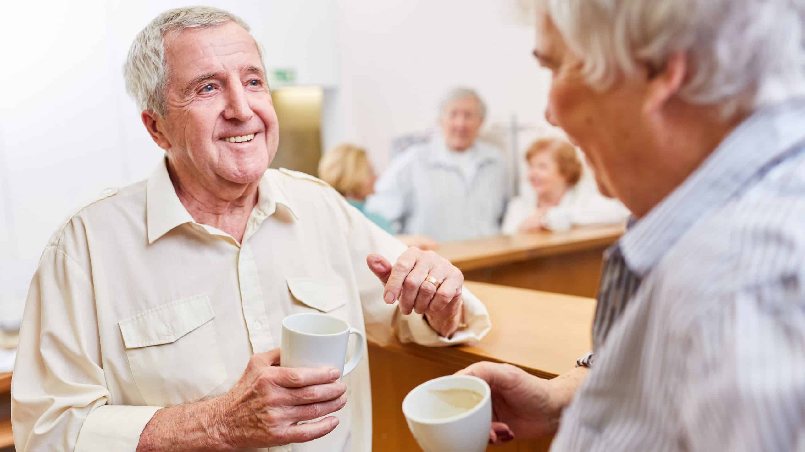 Two seniors talk and flirt with each other in the common room of the retirement home