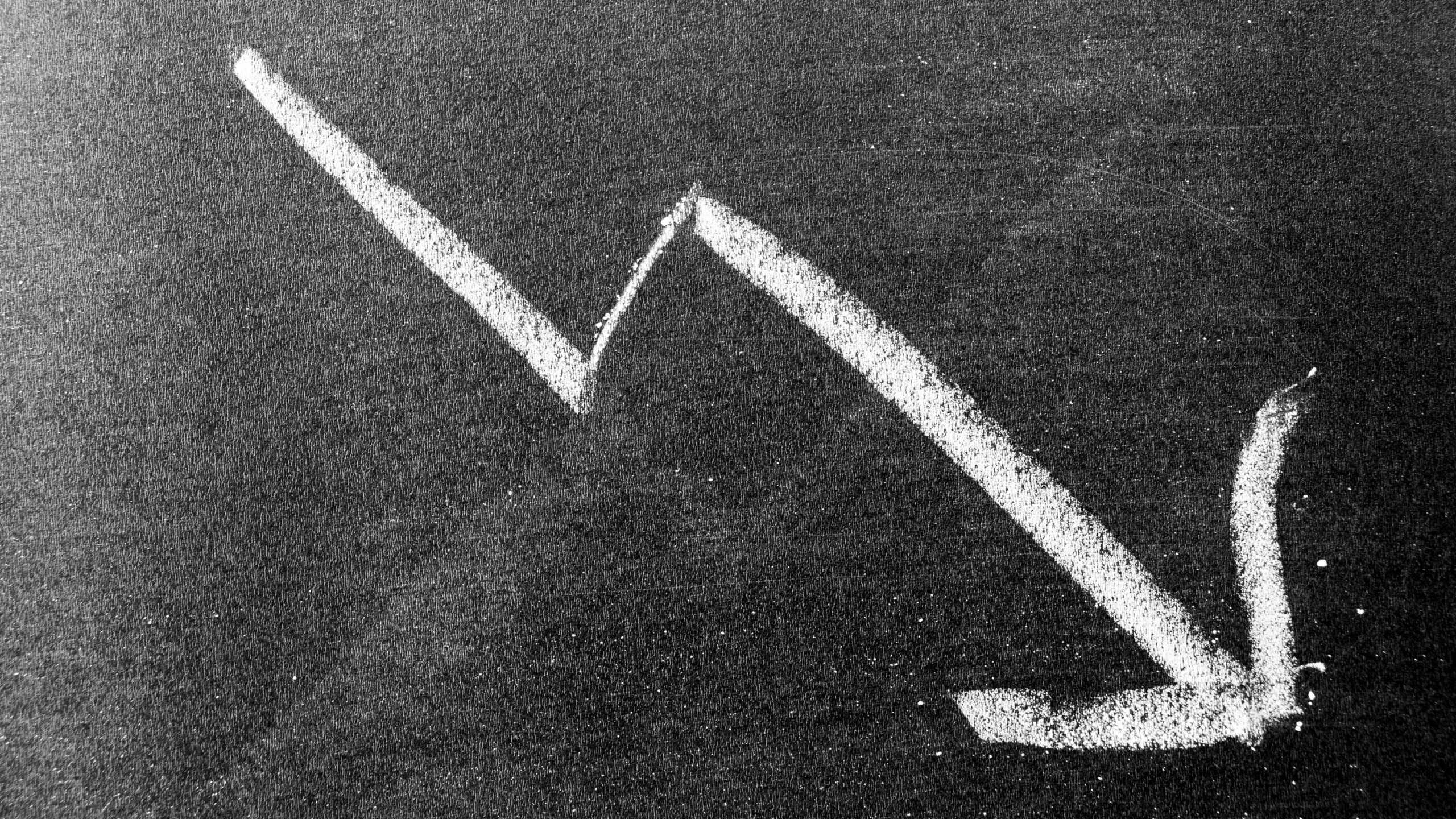 White chalk hand drawing in arrow down shape, decline