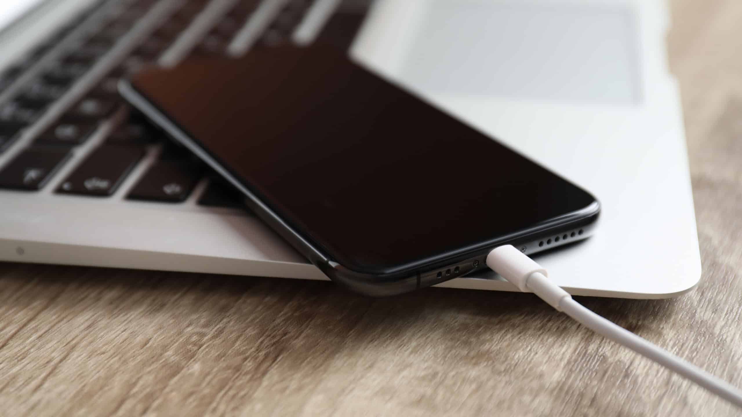 iPhone 11, charge cable and MacBook laptop on wooden table
