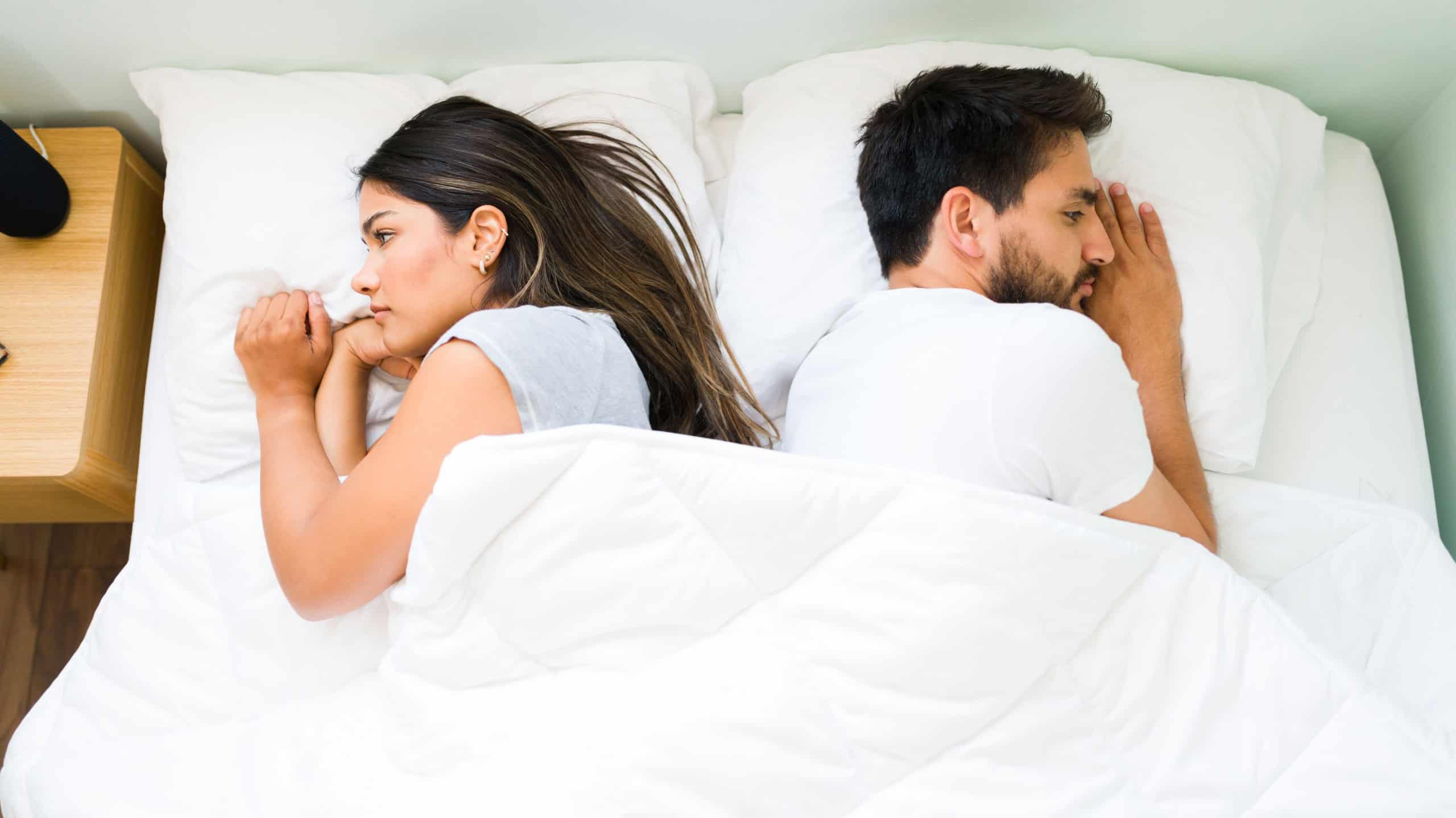 Top view of an attractive couple turning their backs and feeling angry with each other after having a fight before sleep