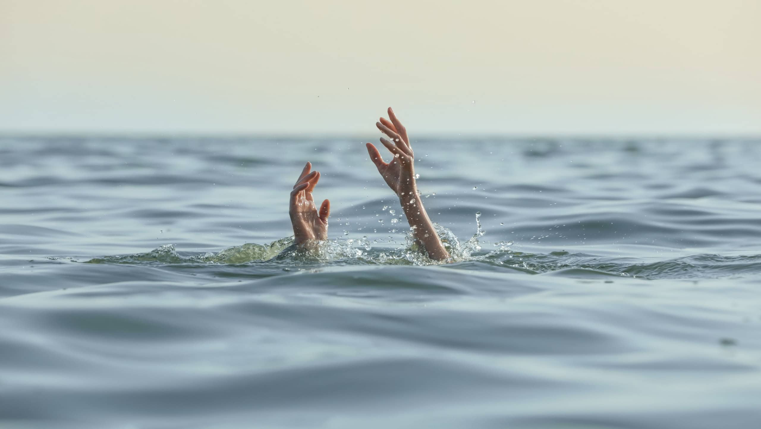 Drowning woman reaching for help in sea