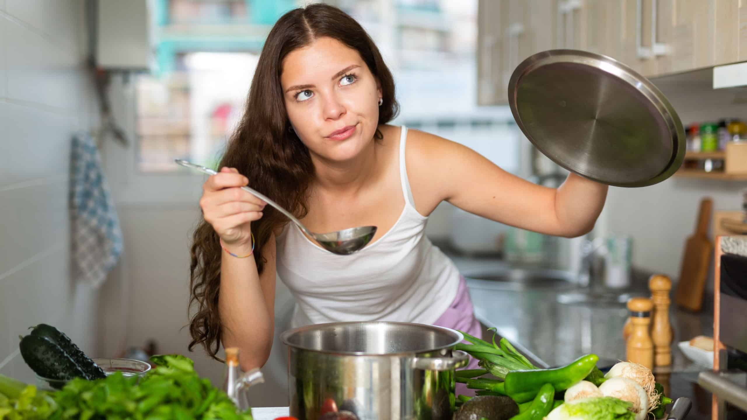 Confused young woman standing at kitchen, having problems in cooking