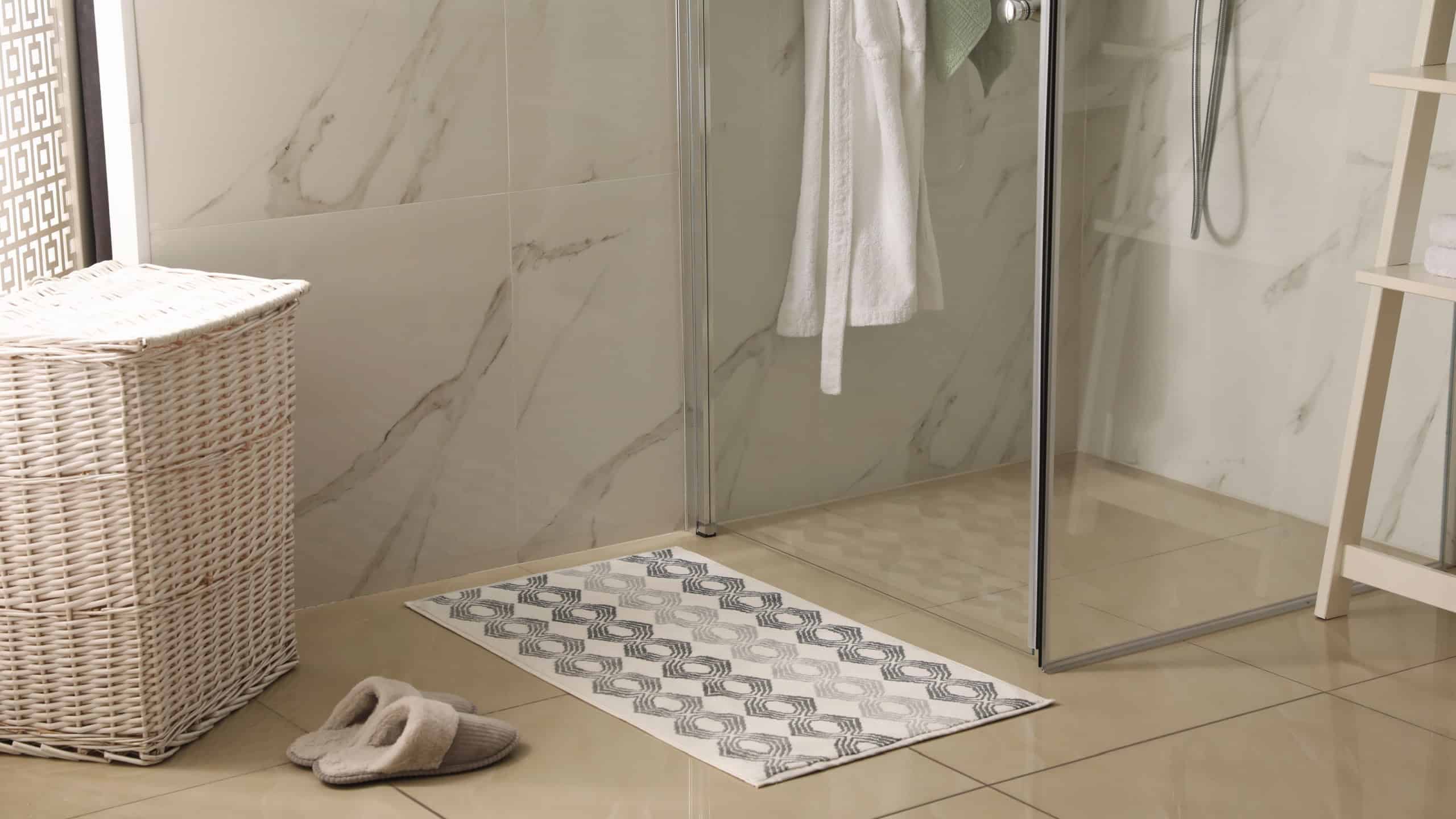 Soft bath mat and slippers on floor in bathroom