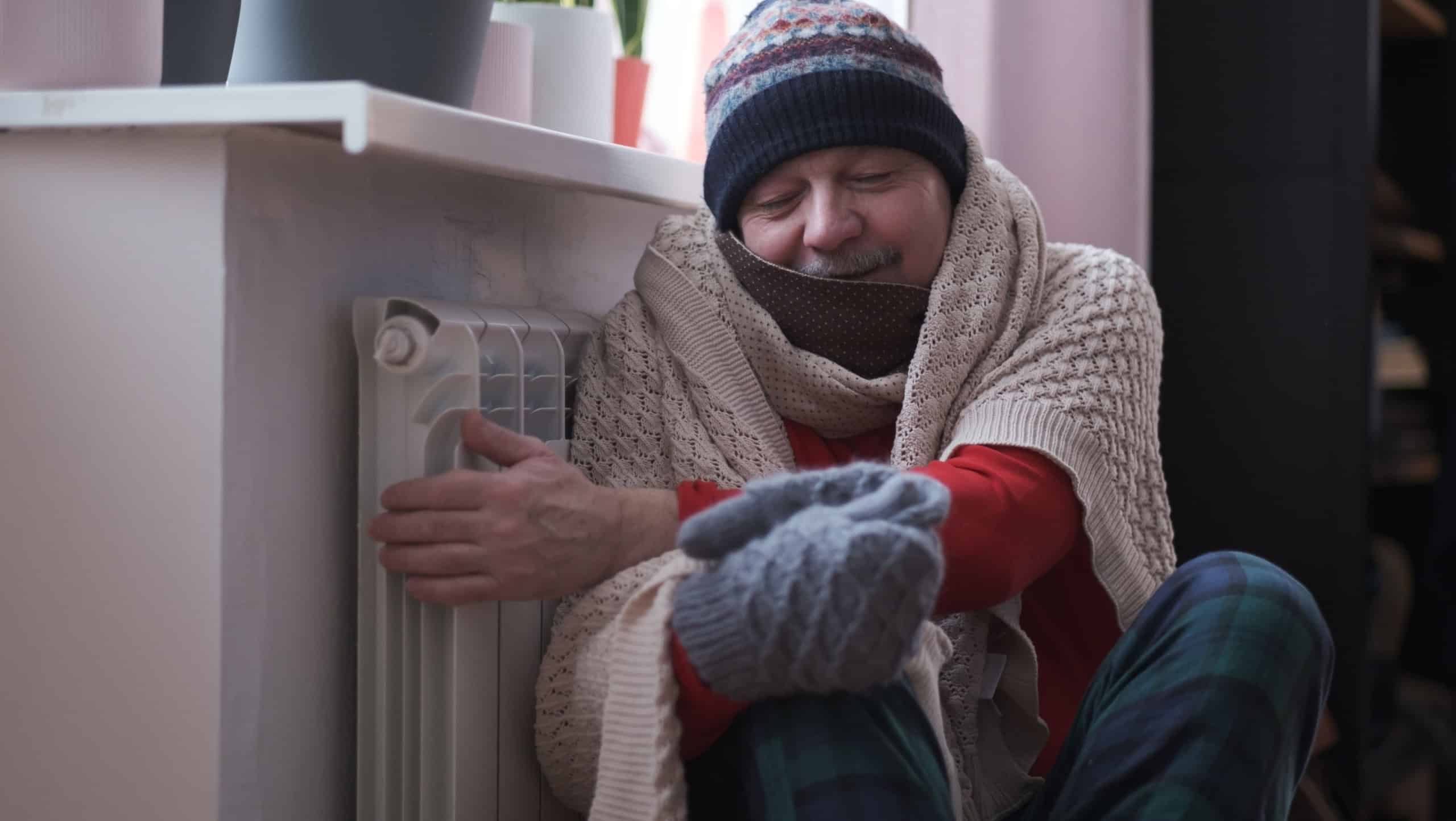Man feeling cold at home with home heating trouble