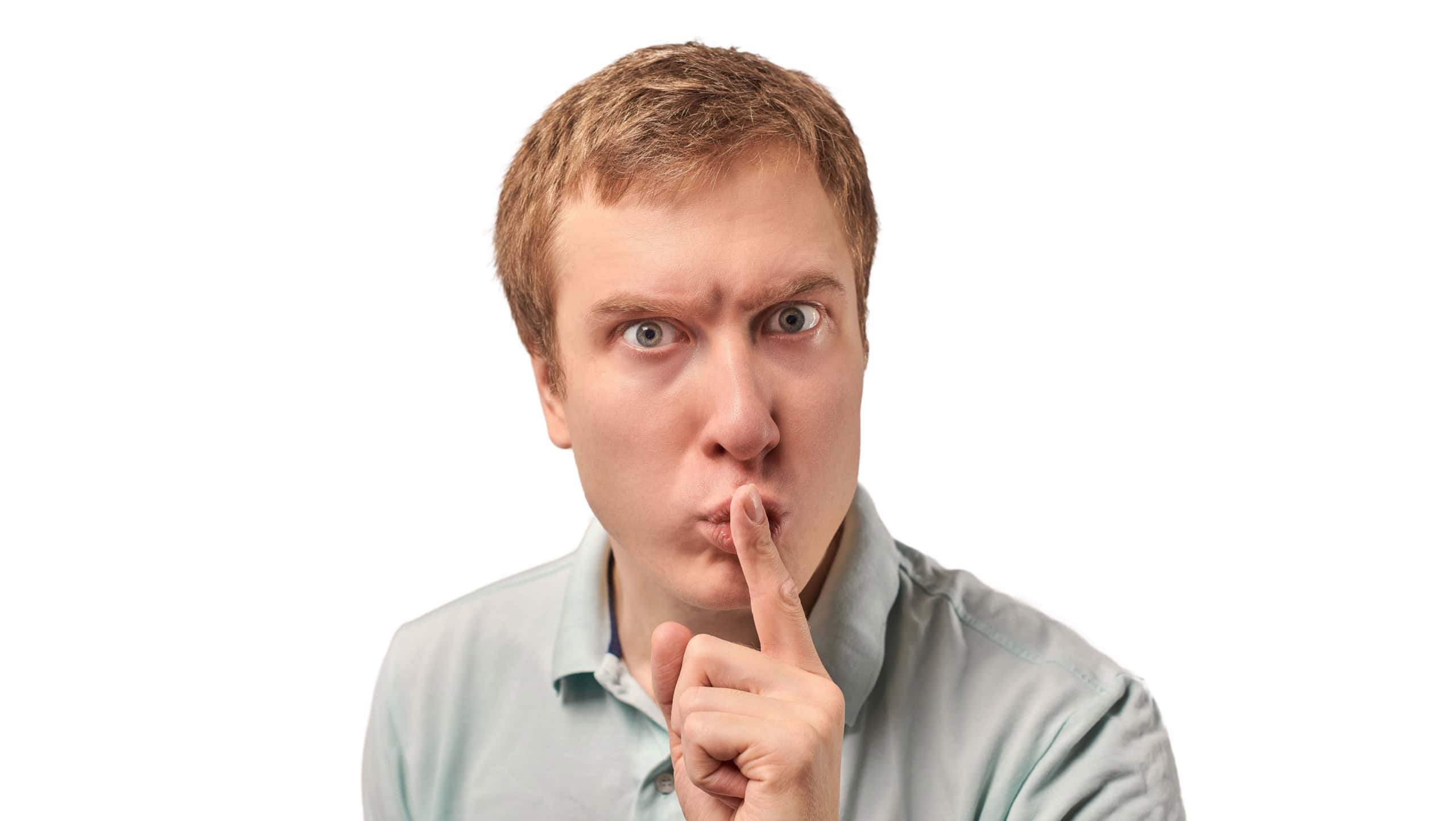 Funny guy in light gray Polo T-shirt asking to be quiet, silence gesture isolated on white background. Young man saying Shhh, keep quiet, please and making silence gesture, request for silence