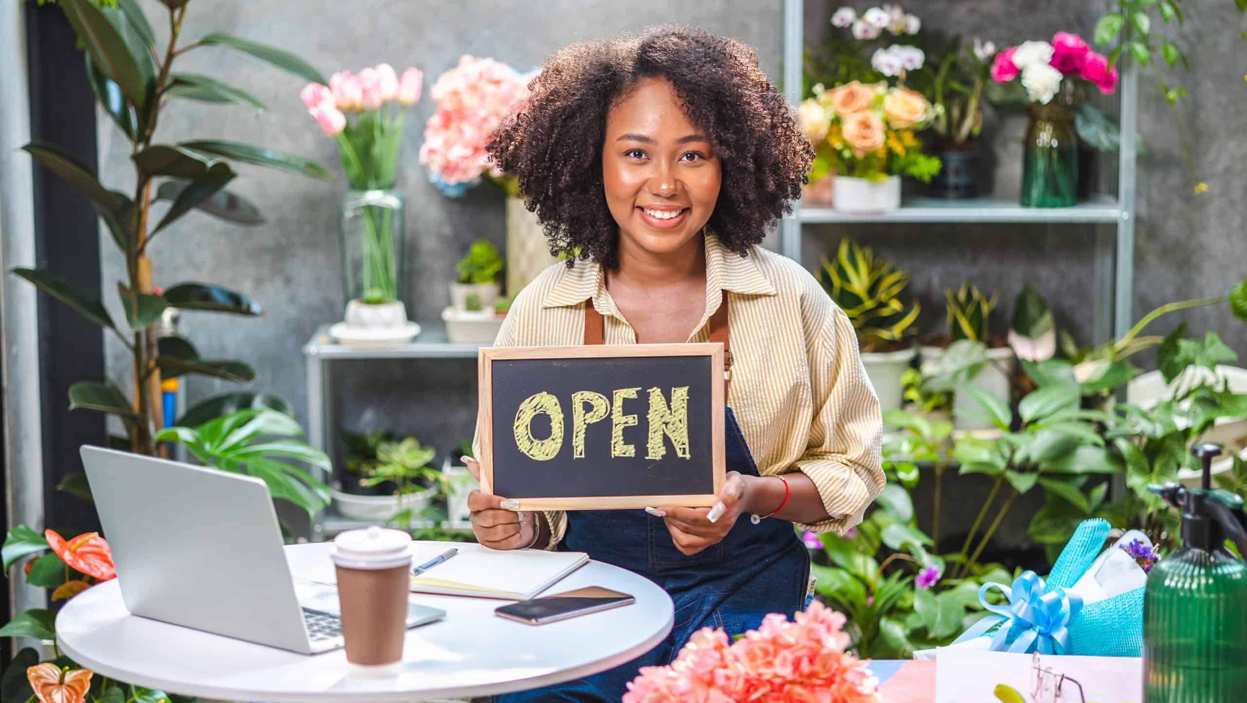African American woman influencer or SME owner people smile work on home video camera selfie shoot.Smiling female florist talking on mobile phone. Young woman working at shop with Open sign.