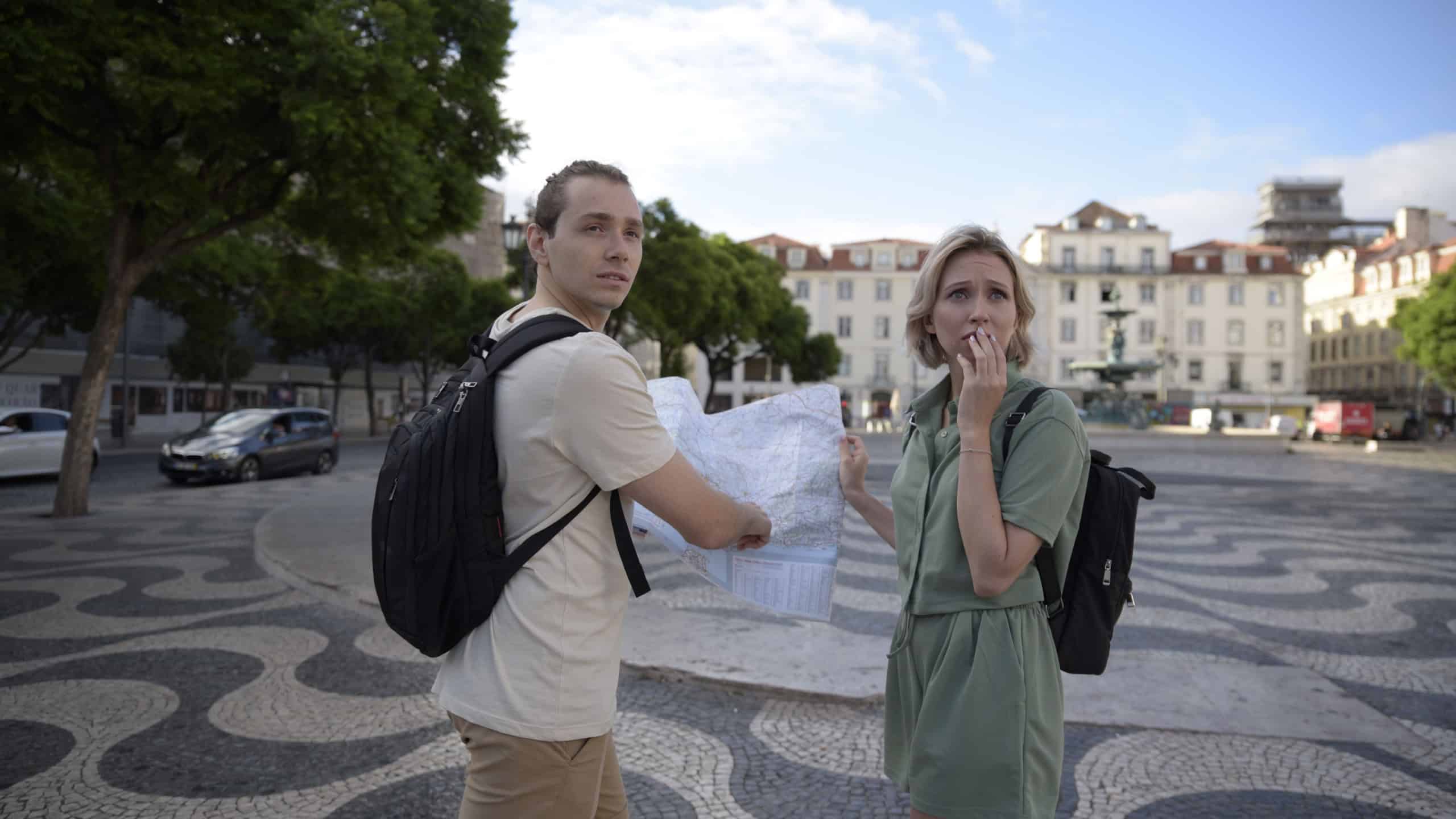 Frustrated tourist couple on square. Man and woman looking back with map in hands. Portrait, travelling concept