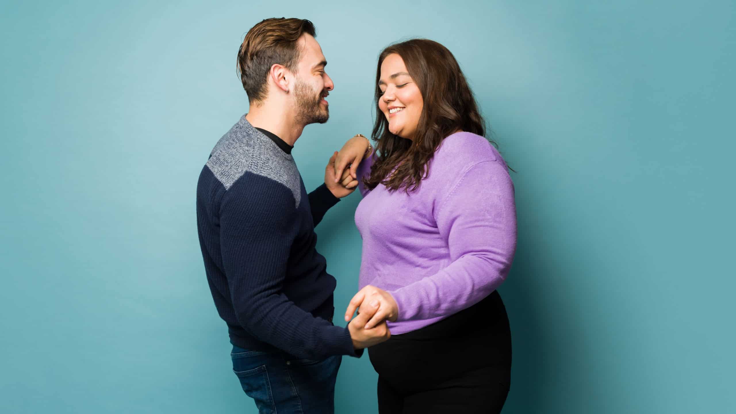 Loving beautiful young couple holding hands and dancing together during a romantic date