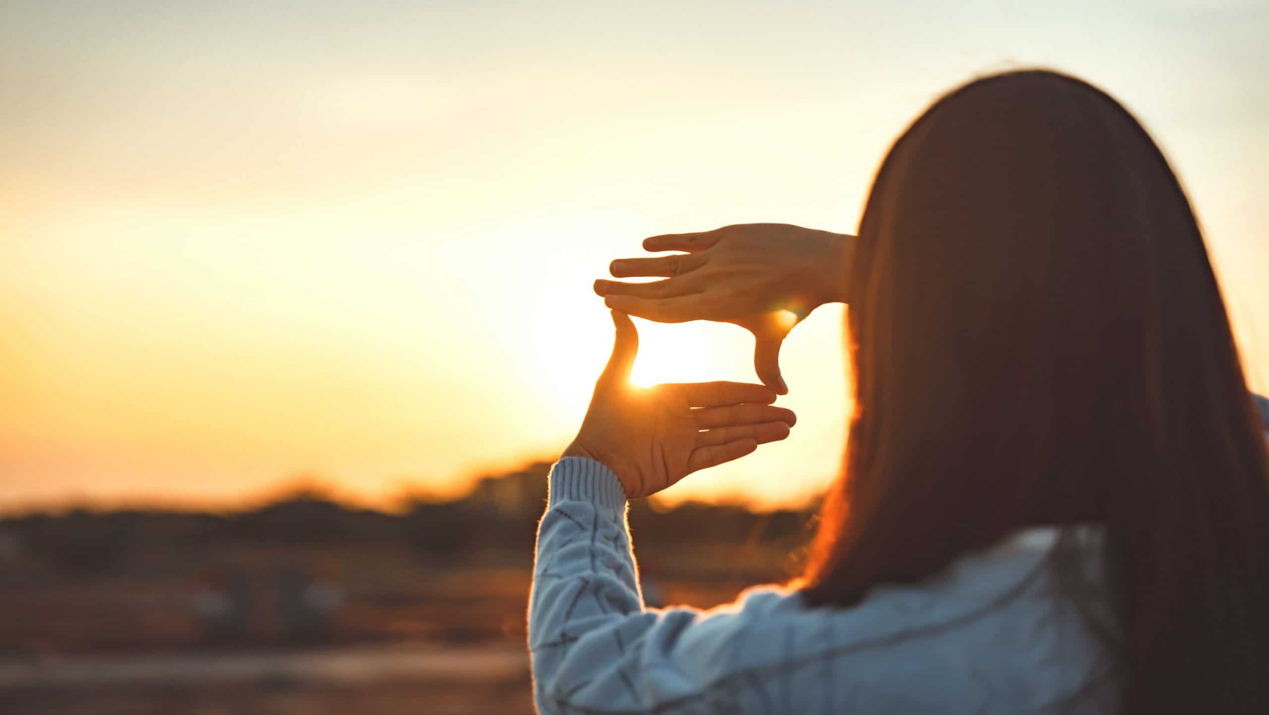 Woman hands making frame gesture with sunset, Female capturing the sunrise. Business planning, strategy and vision concept.