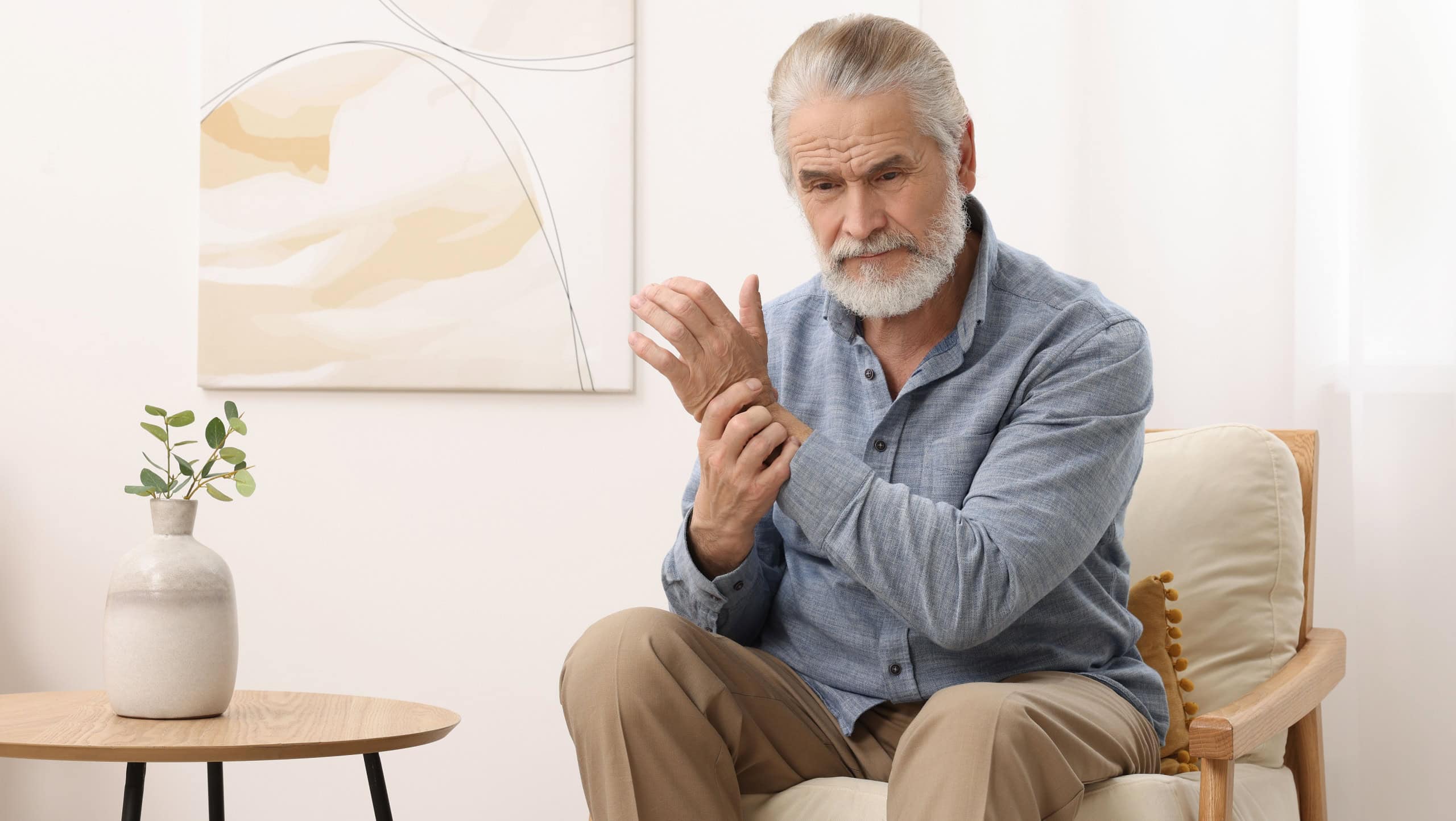 Senior man suffering from pain in his wrist at home. Arthritis symptoms