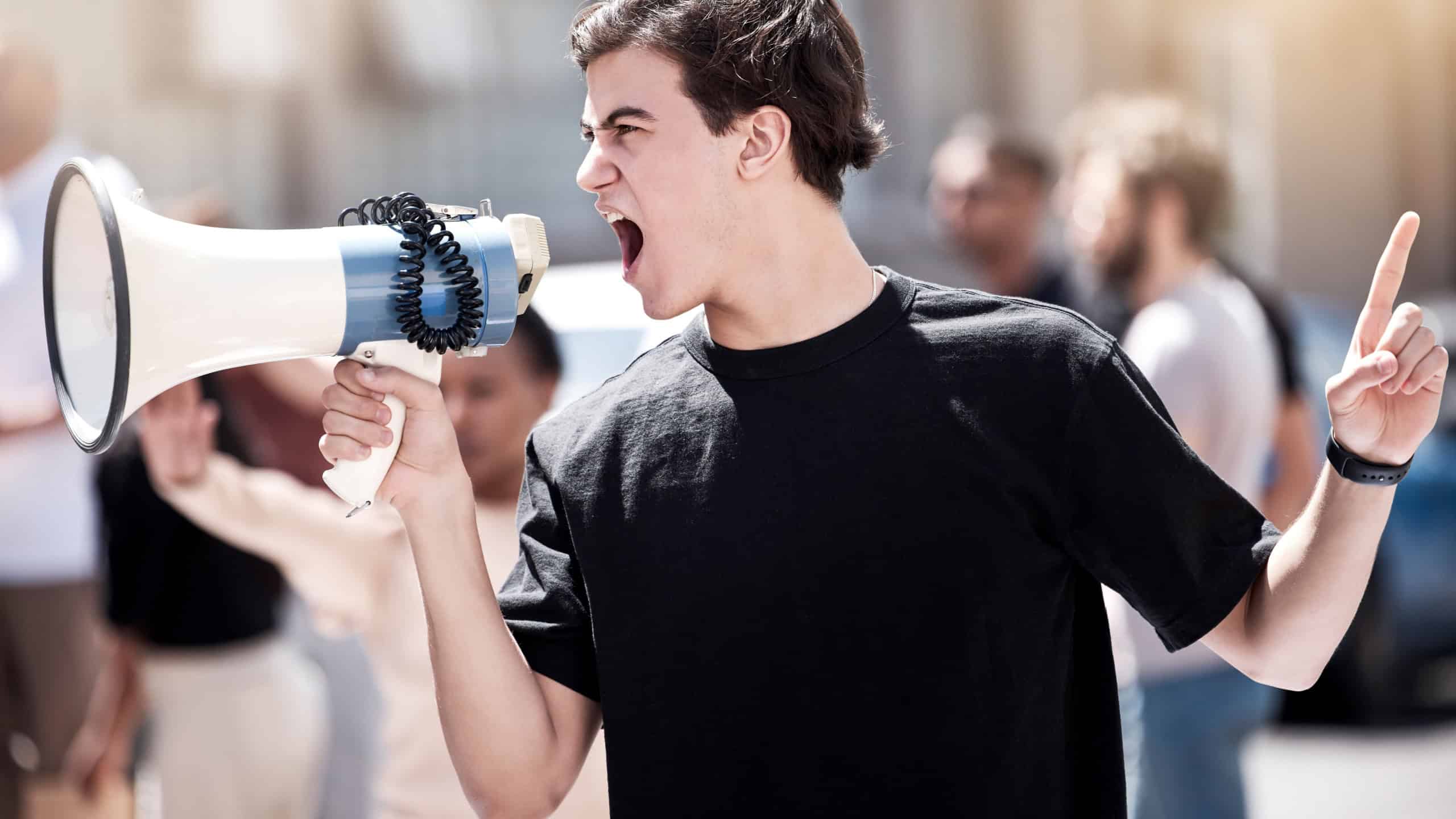 We will not be silenced. Shot of a young man yelling through a megaphone during a protest.