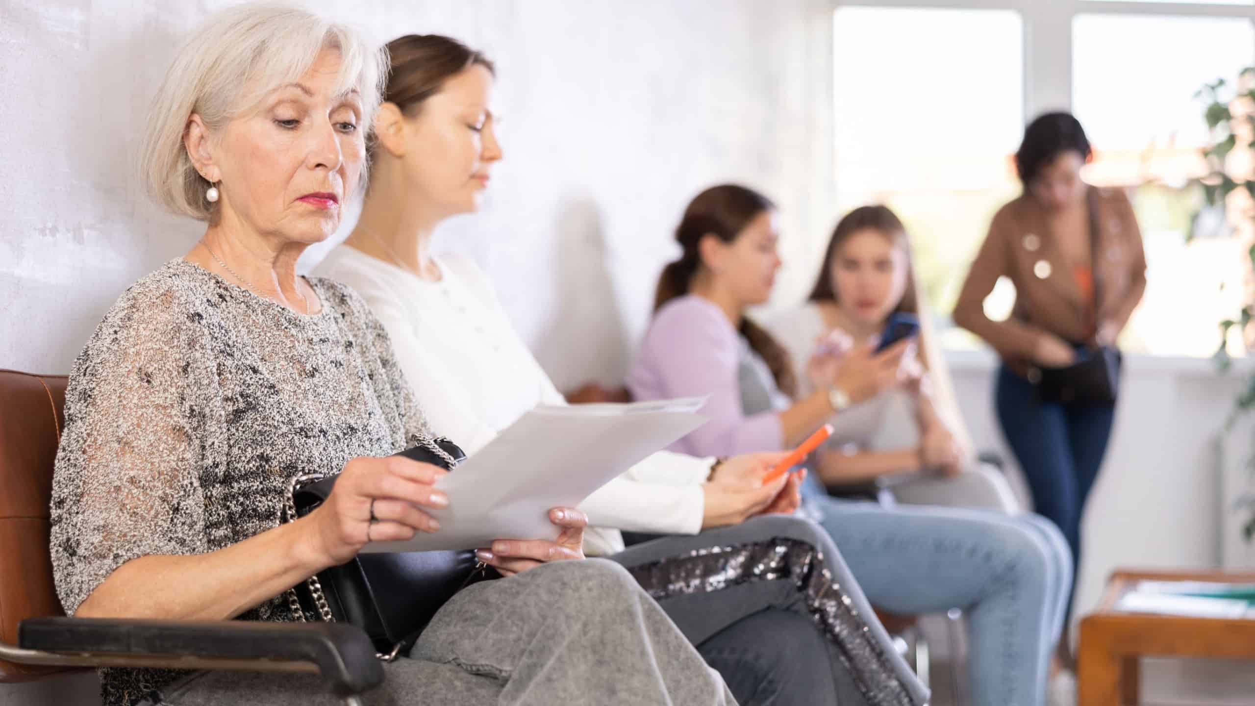 Elderly woman looking through documents while waiting for an appointment with a specialist in the office