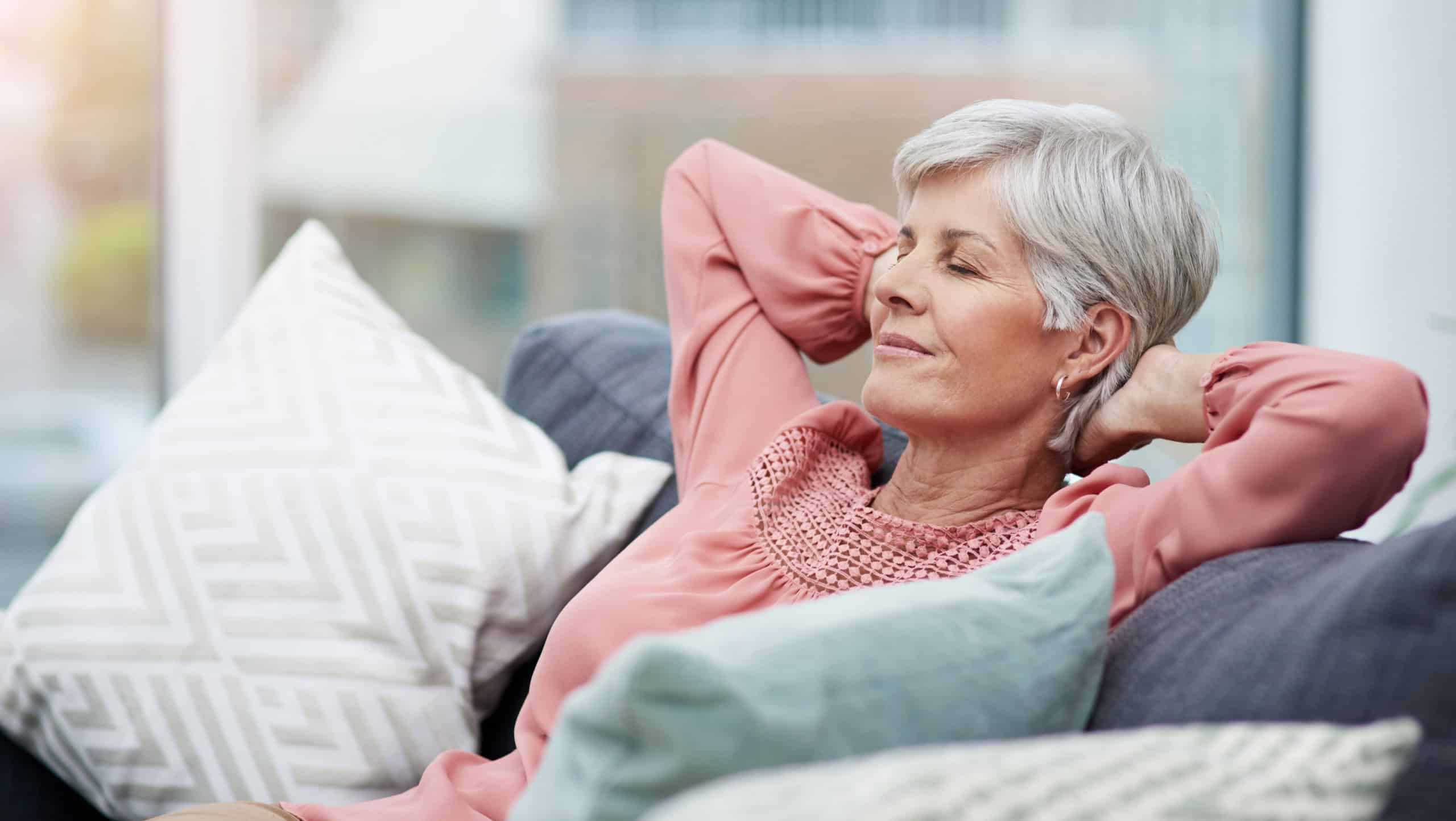 Senior woman, relief and relax on sofa in home living room with peace, silence and happiness with free time. Elderly lady, retirement and lounge couch with freedom, sleep and happy for lifestyle