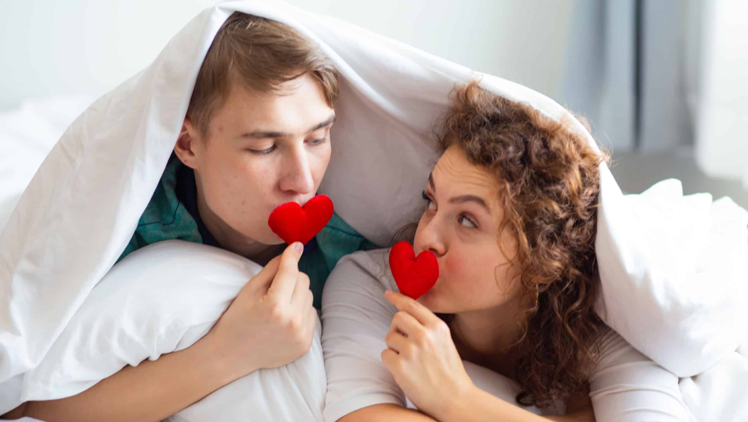 Love couple lying on bed white blanket holding red heart happy romantic life