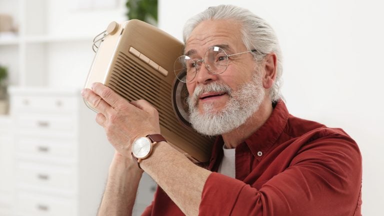 Senior man with retro radio receiver at home