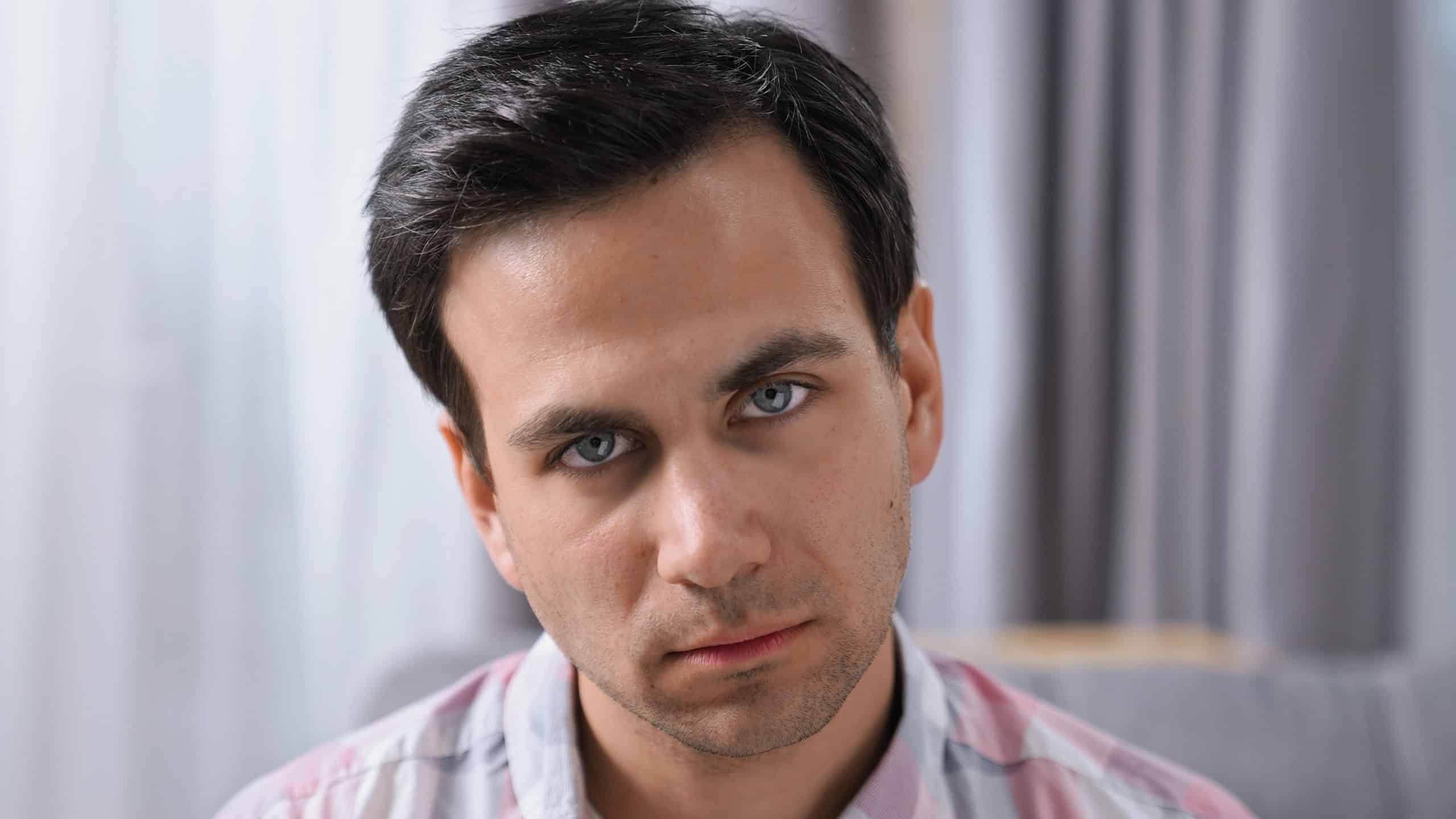 Brutal displeased 30s person look camera. Young adult guy head shot. Annoyed angry man portrait. One rude male face close up. Bad day mood. Scary tired mad gaze. Anger grim emotion. Black hair bristle