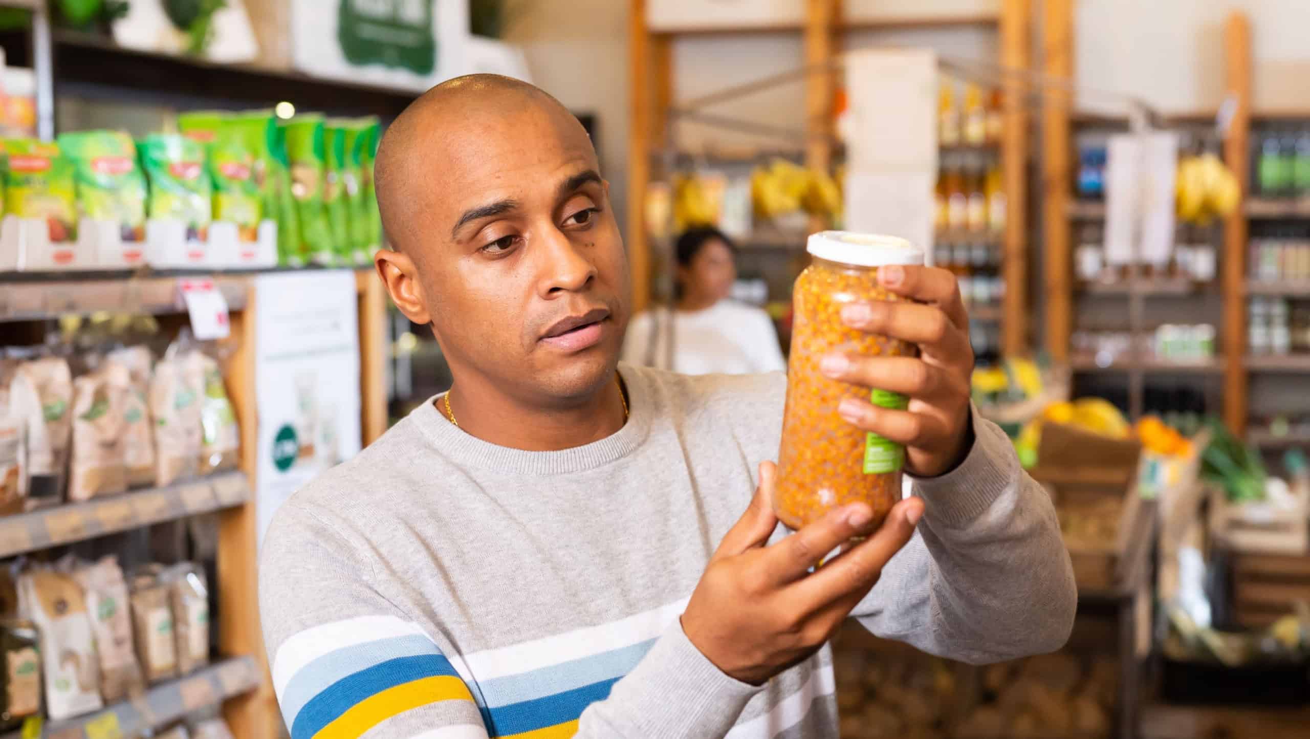 Adult positive man is choosing conserve in grocery supermarket