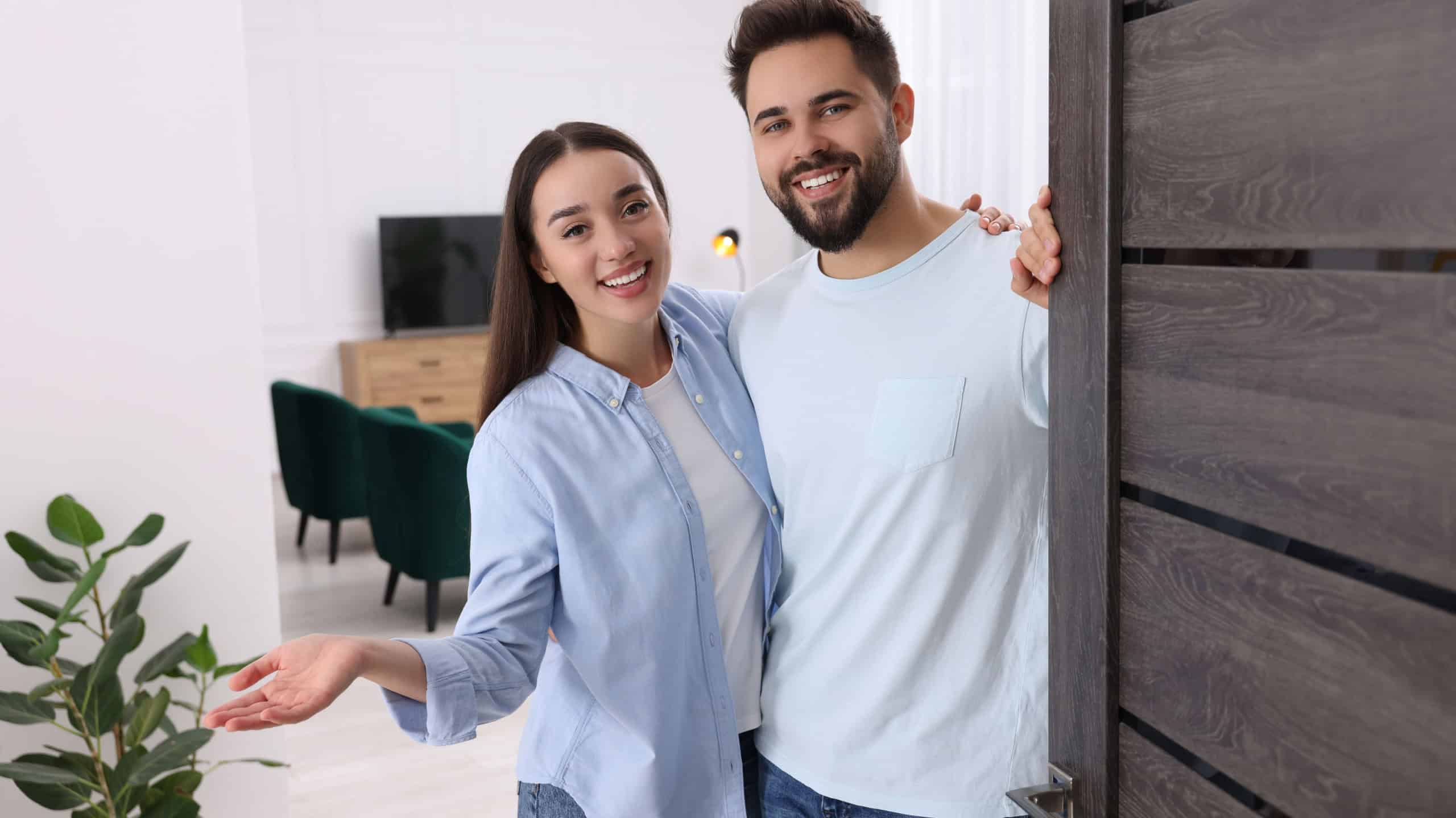 Happy couple welcoming near door. Invitation to come indoors