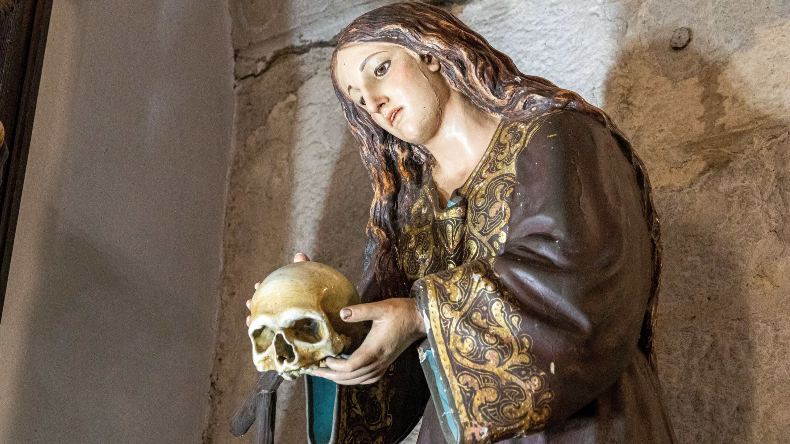 Wooden sculpture representing Saint Mary Magdalene holding a human skull