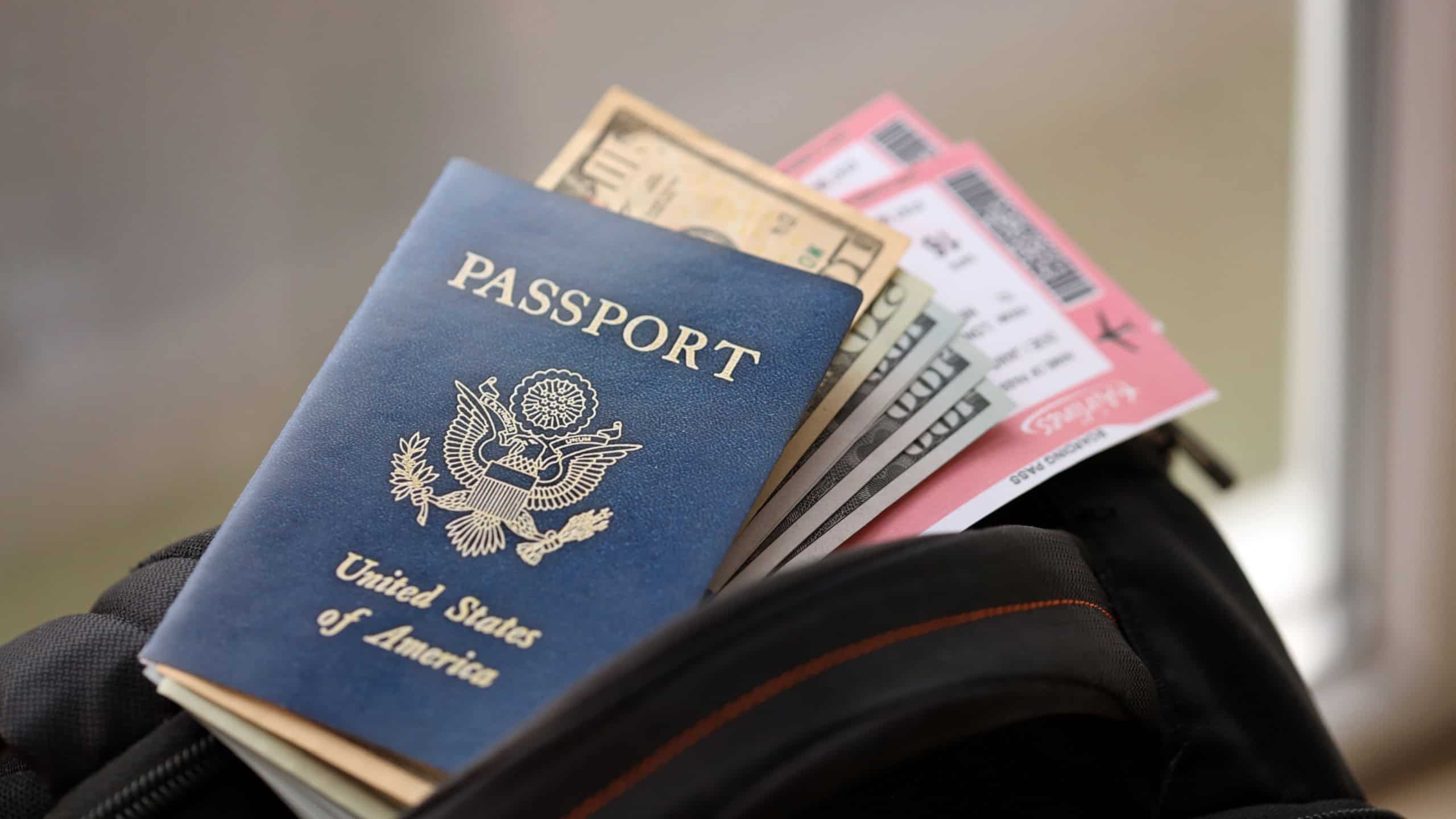 Blue United States of America passport with money and airline tickets on touristic backpack close up. Tourism and travel concept