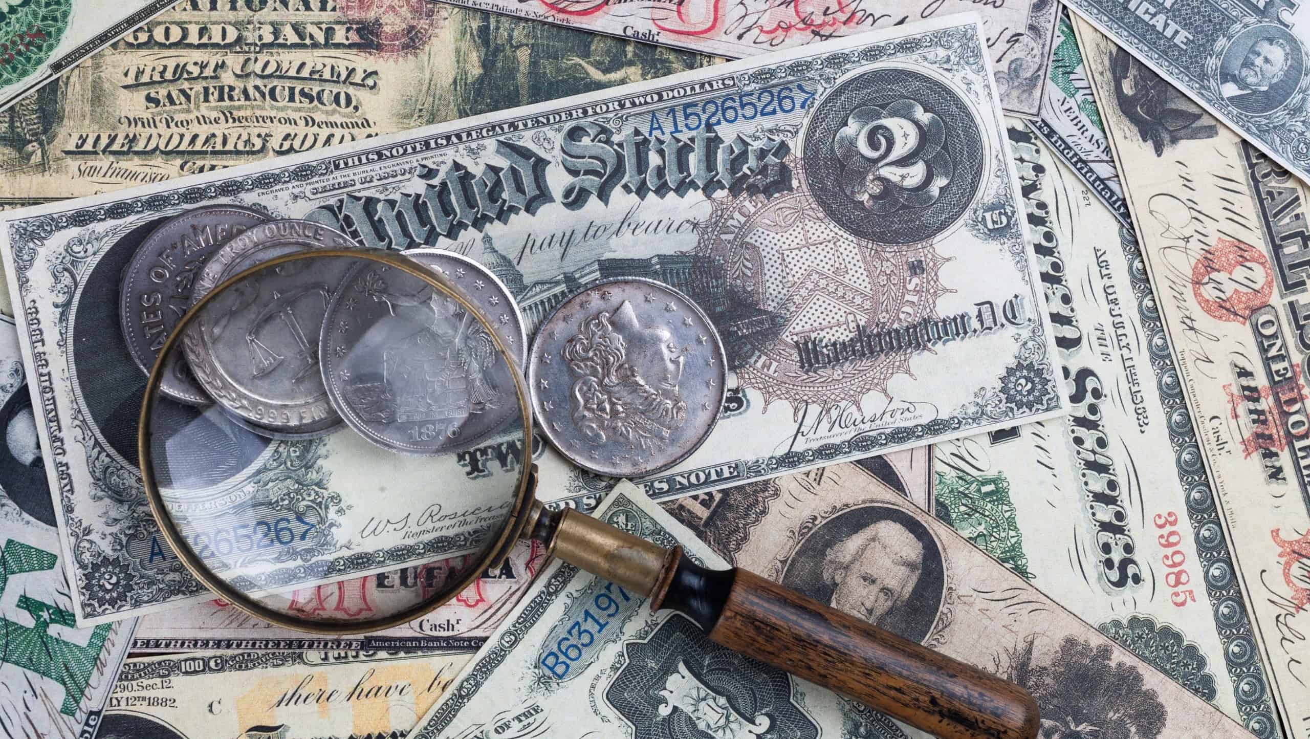 Old US banknotes and silver certificates with silver dollar coins and magnifying glass background