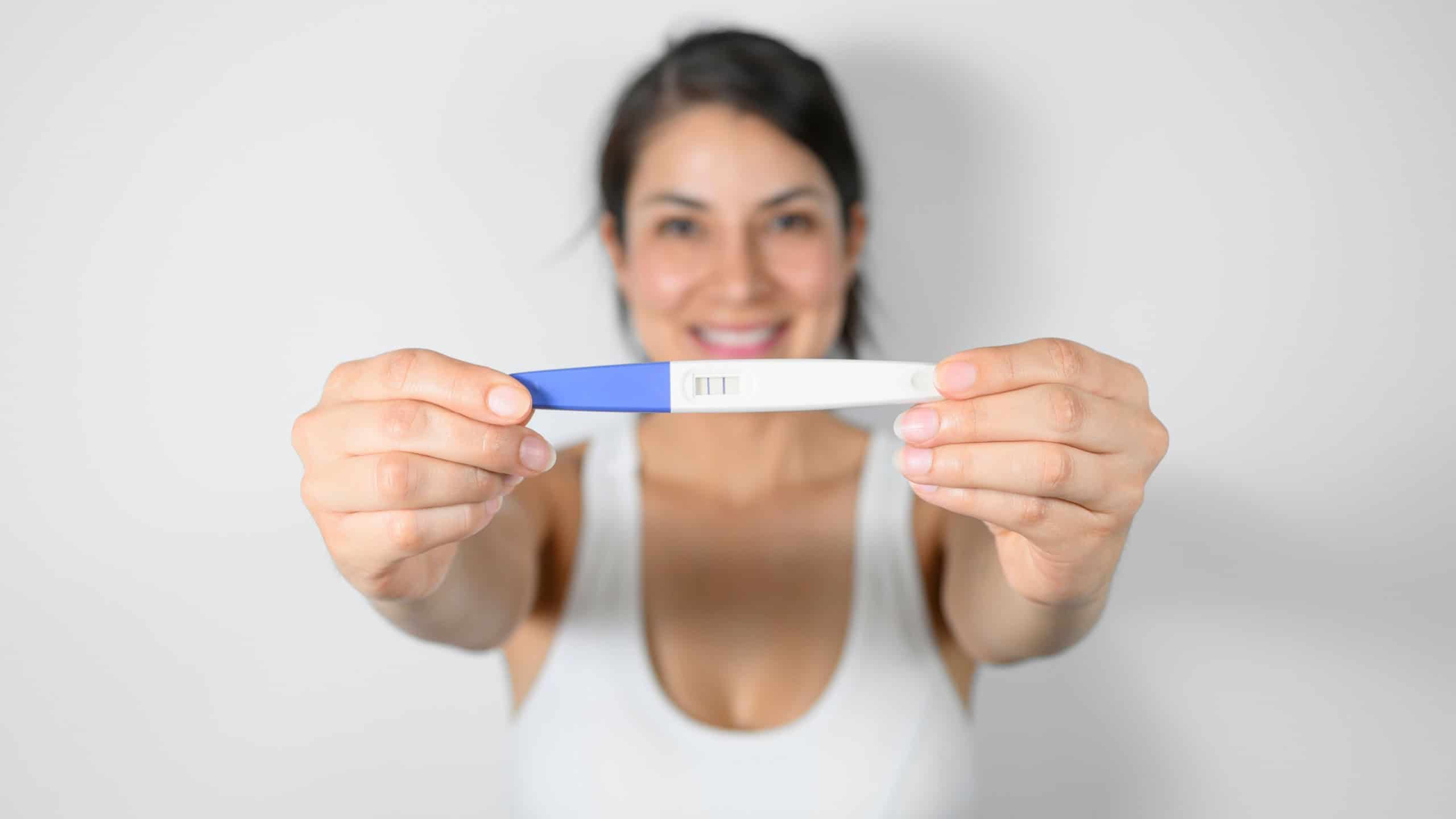 Close up pregnant woman holds a positive pregnancy test, selective focus. motherhood concept