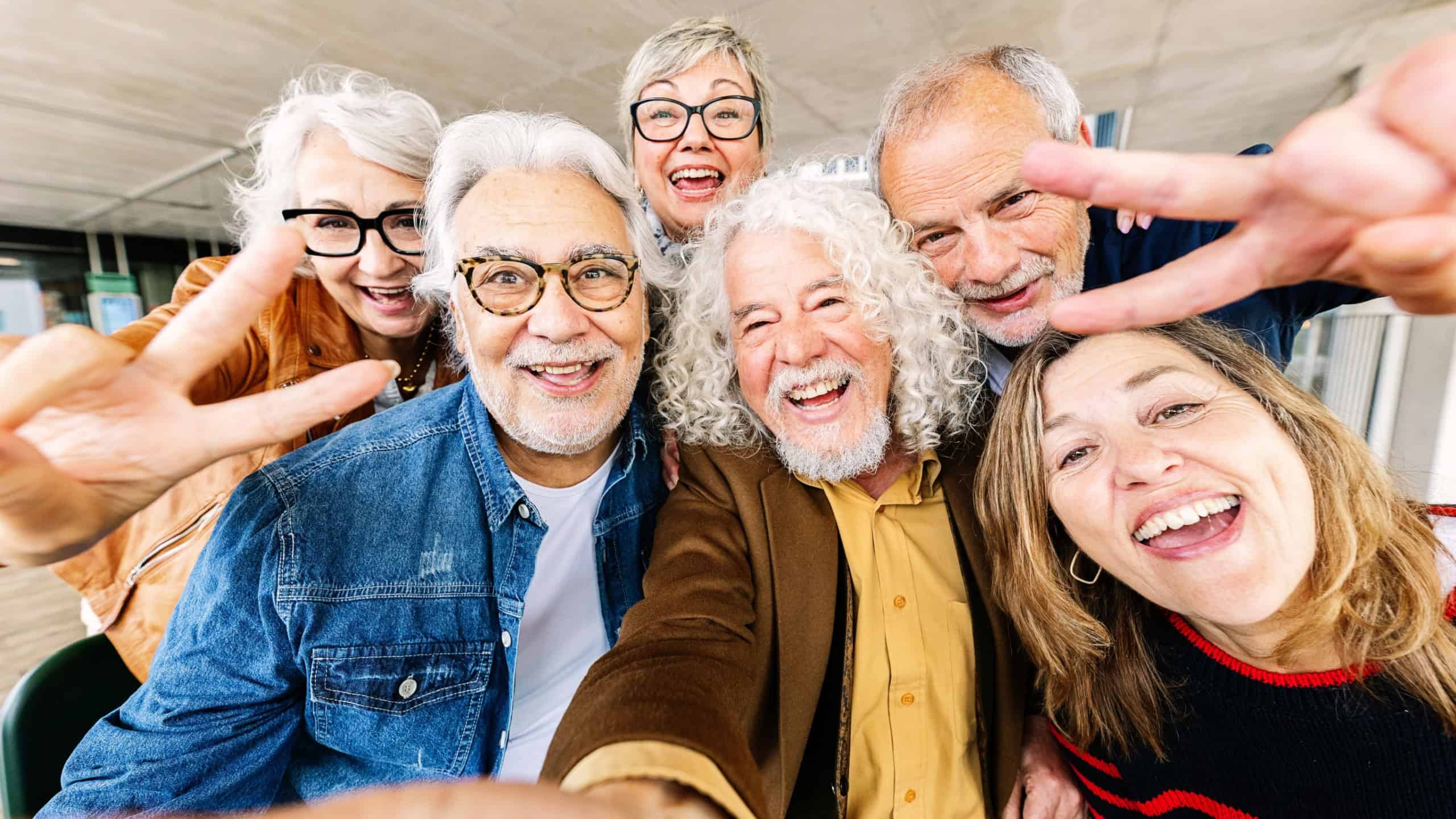 Joyful portrait of senior group of retired people enjoying time together taking selfie photo with phone.