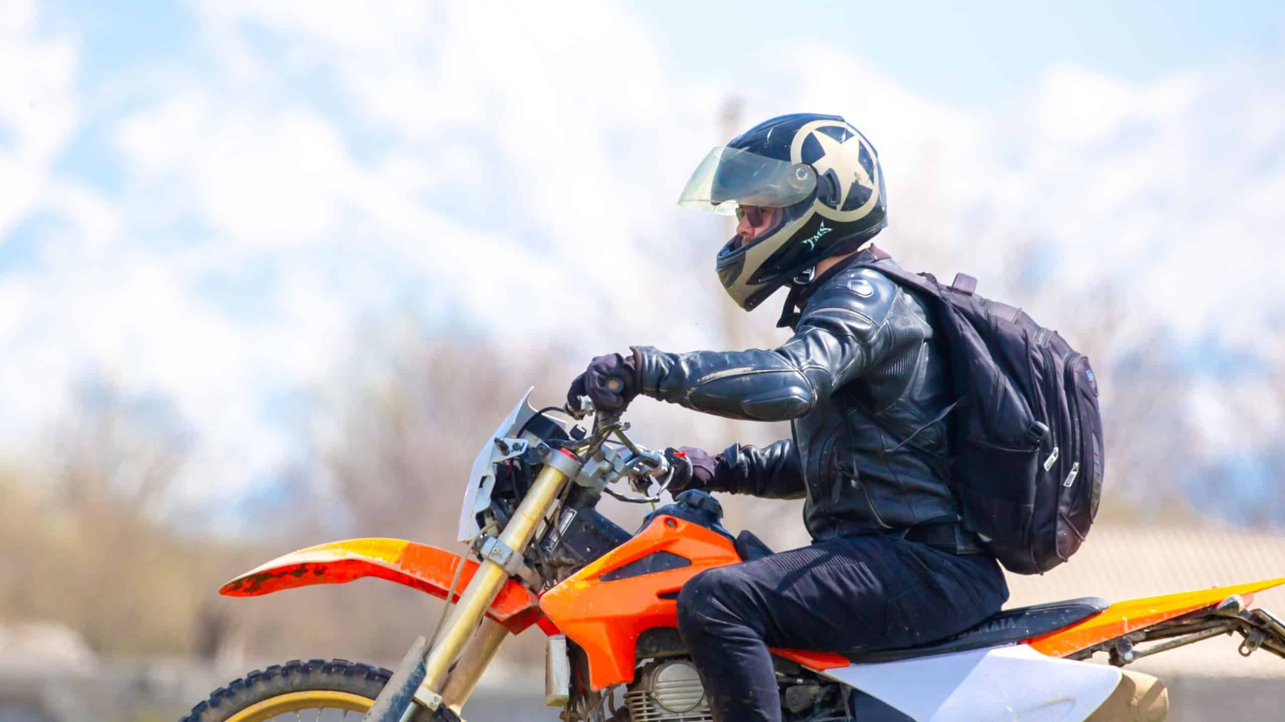 A motorcyclist rides an enduro motorcycle off-road.