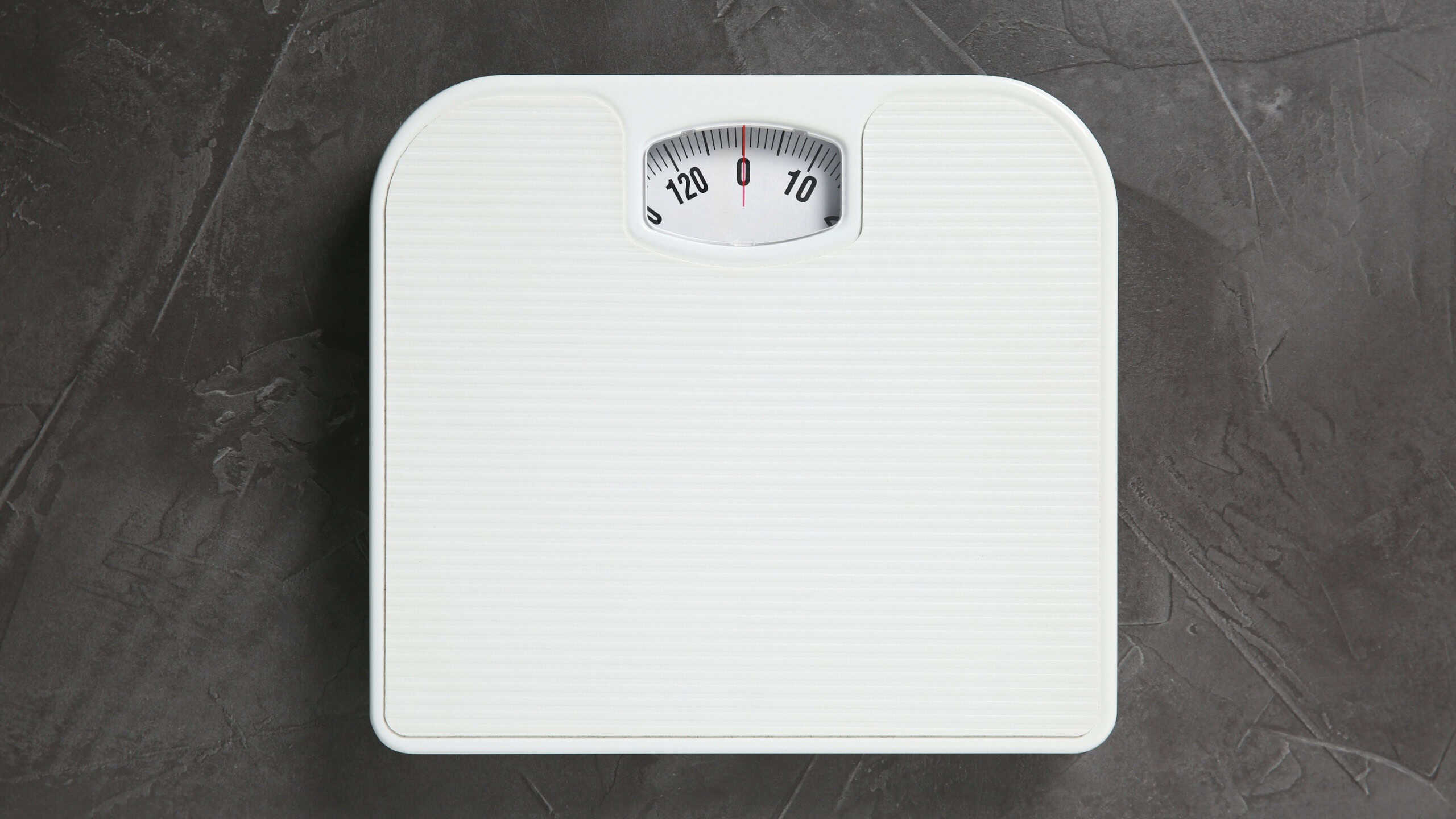 One bathroom scale on grey textured background, top view