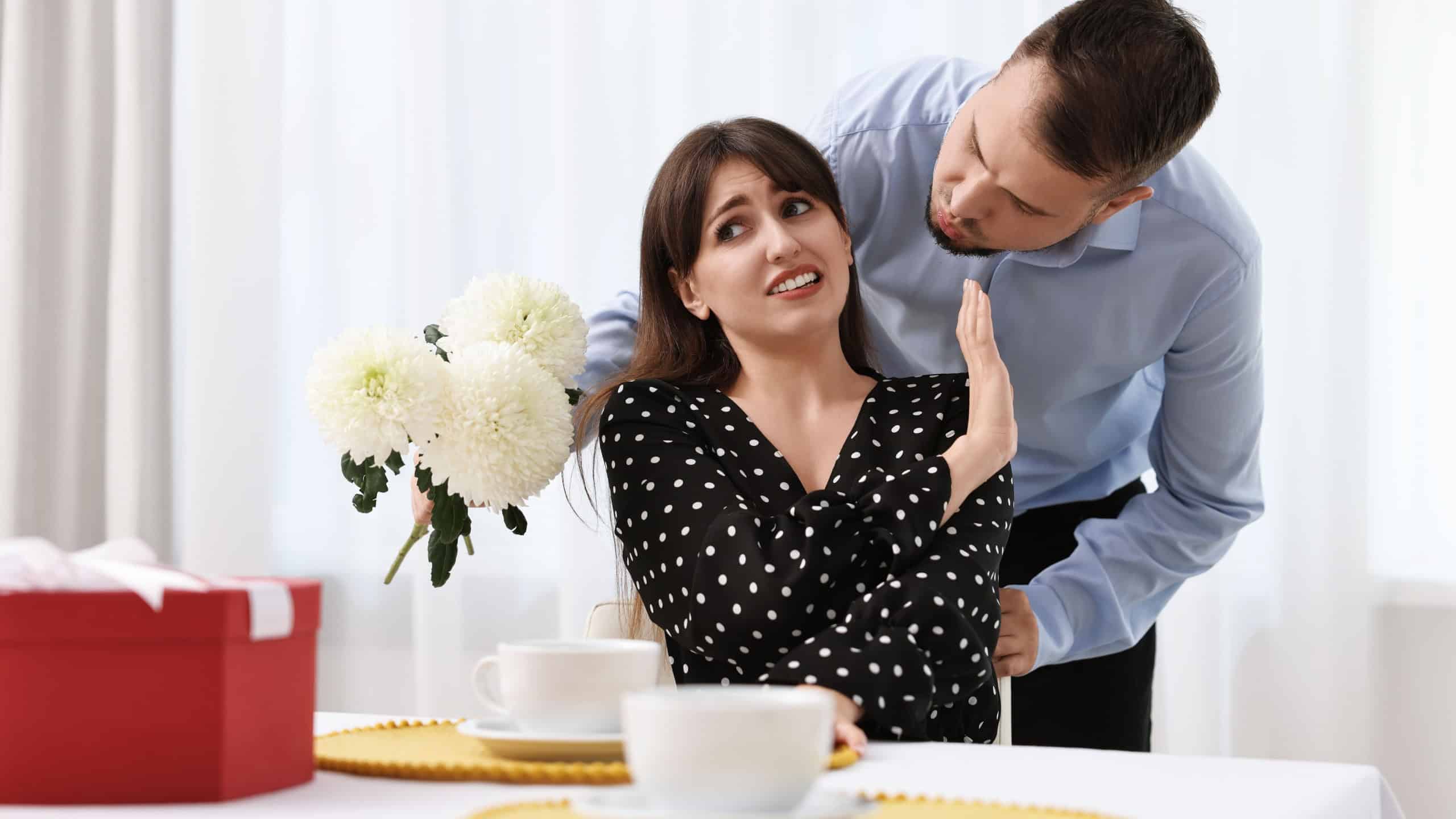 Bad date. Embarrassed woman refusing from man's kiss indoors
