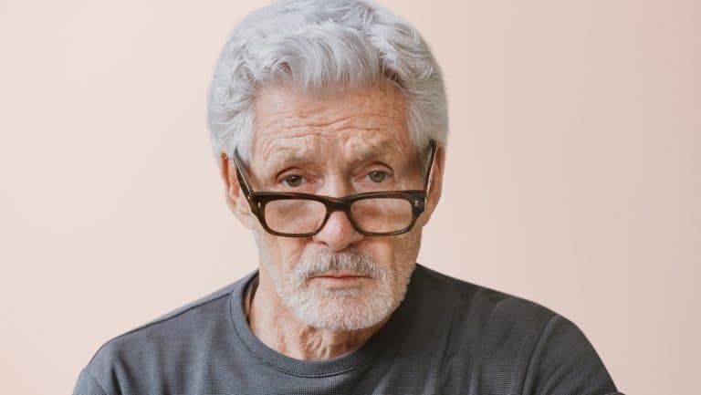 Serious teacher wearing glasses, isolated on pink . Senior caucasian man with gray hair. Senior man wearing glasses. Senior man looking serious, close up. Teacher looking angry and moody.