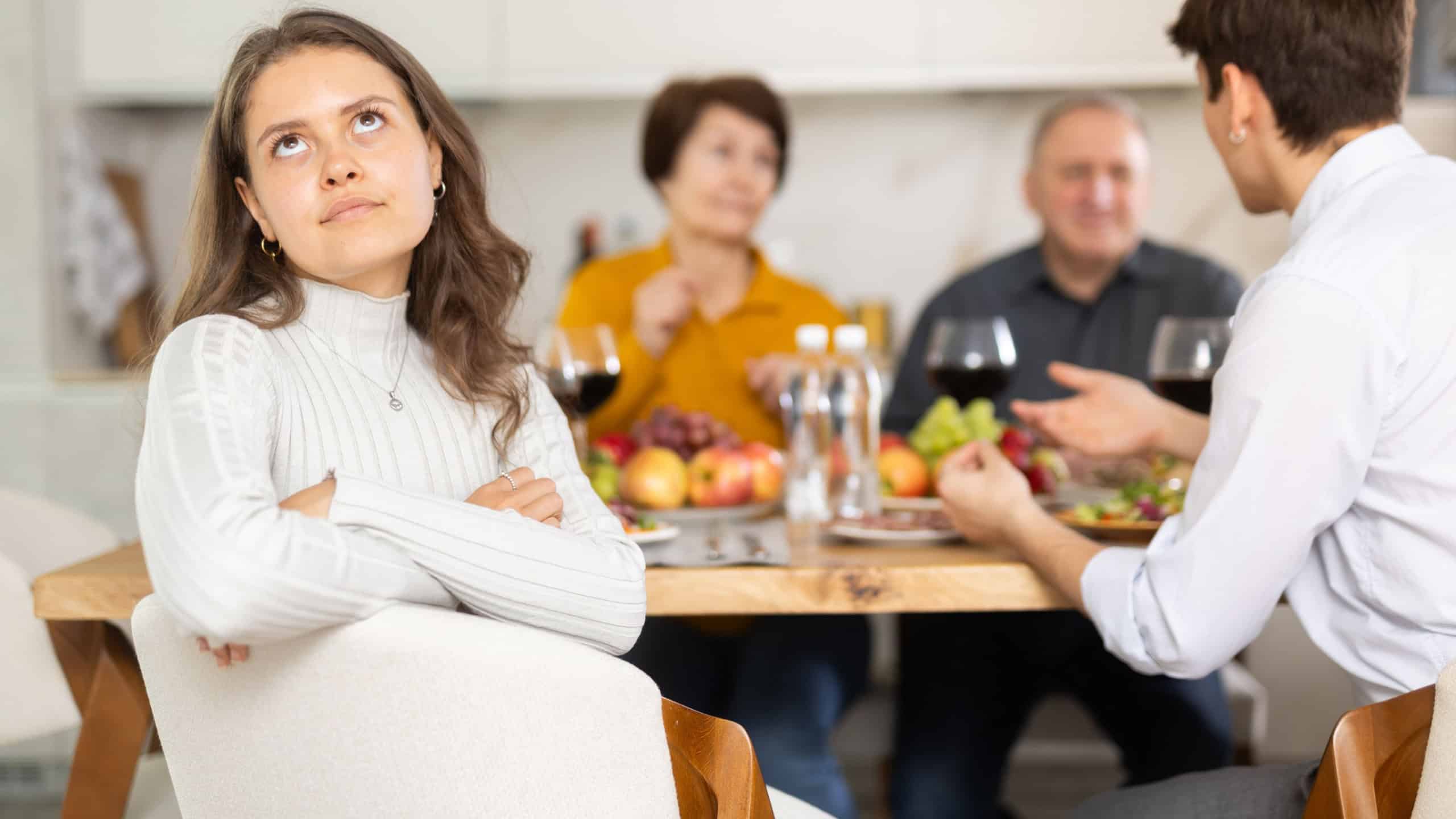 Upset young woman at family holiday table with parents at home. Unpleasant discussion