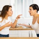 Female friends sorting out relationship. Two irritated young Latinas arguing noisily and emotionally gesturing in cozy home kitchen