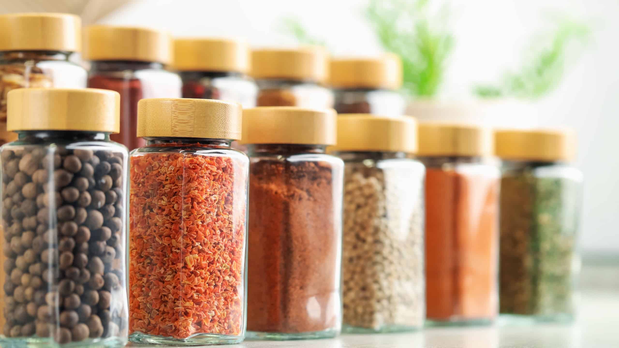 Many different aromatic spices in jars on table indoors, closeup