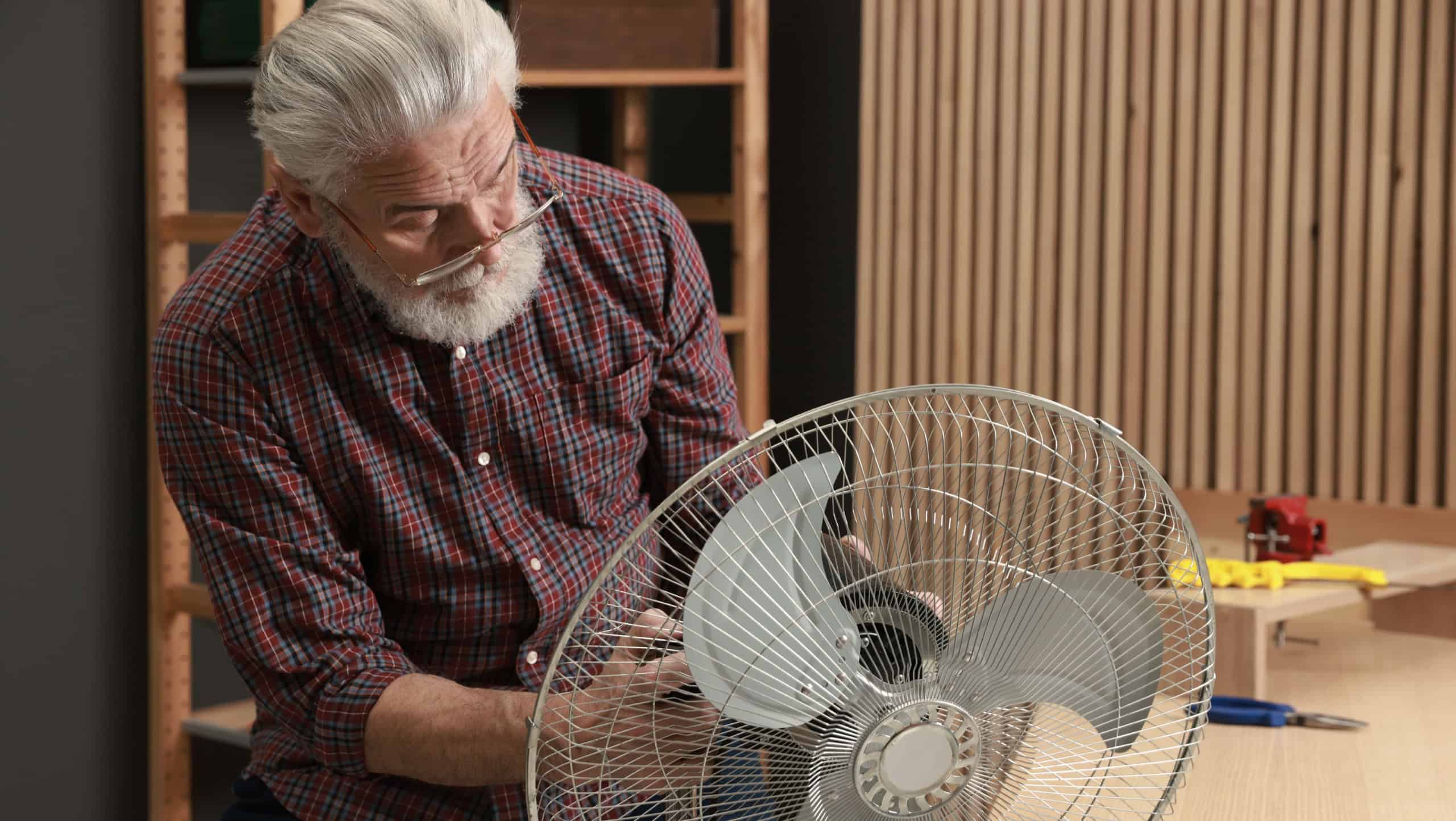 Relaxing hobby. Senior man repairing fan in workshop