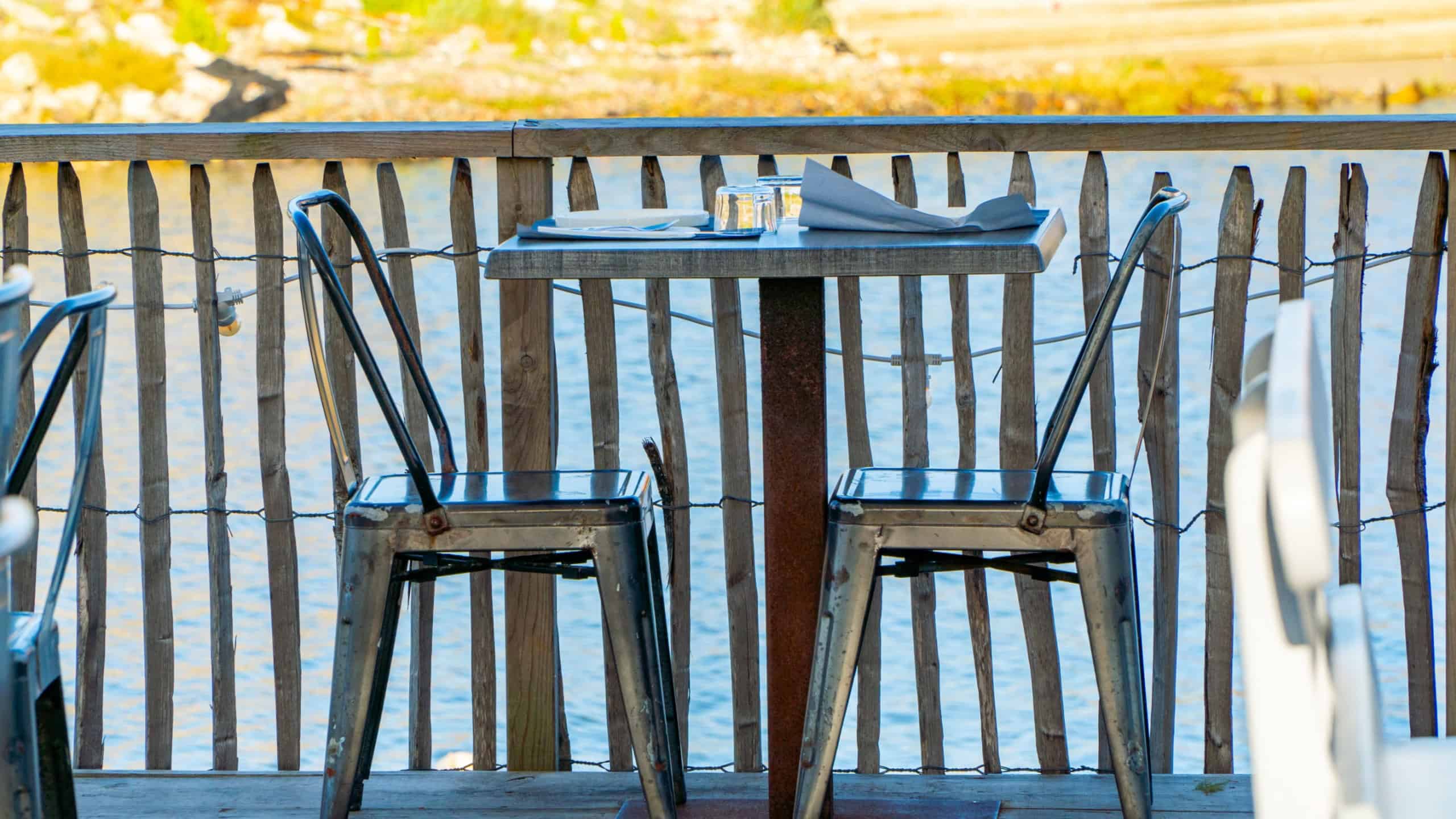 Outdoor restaurant table setup in a fishing harbor at sunset