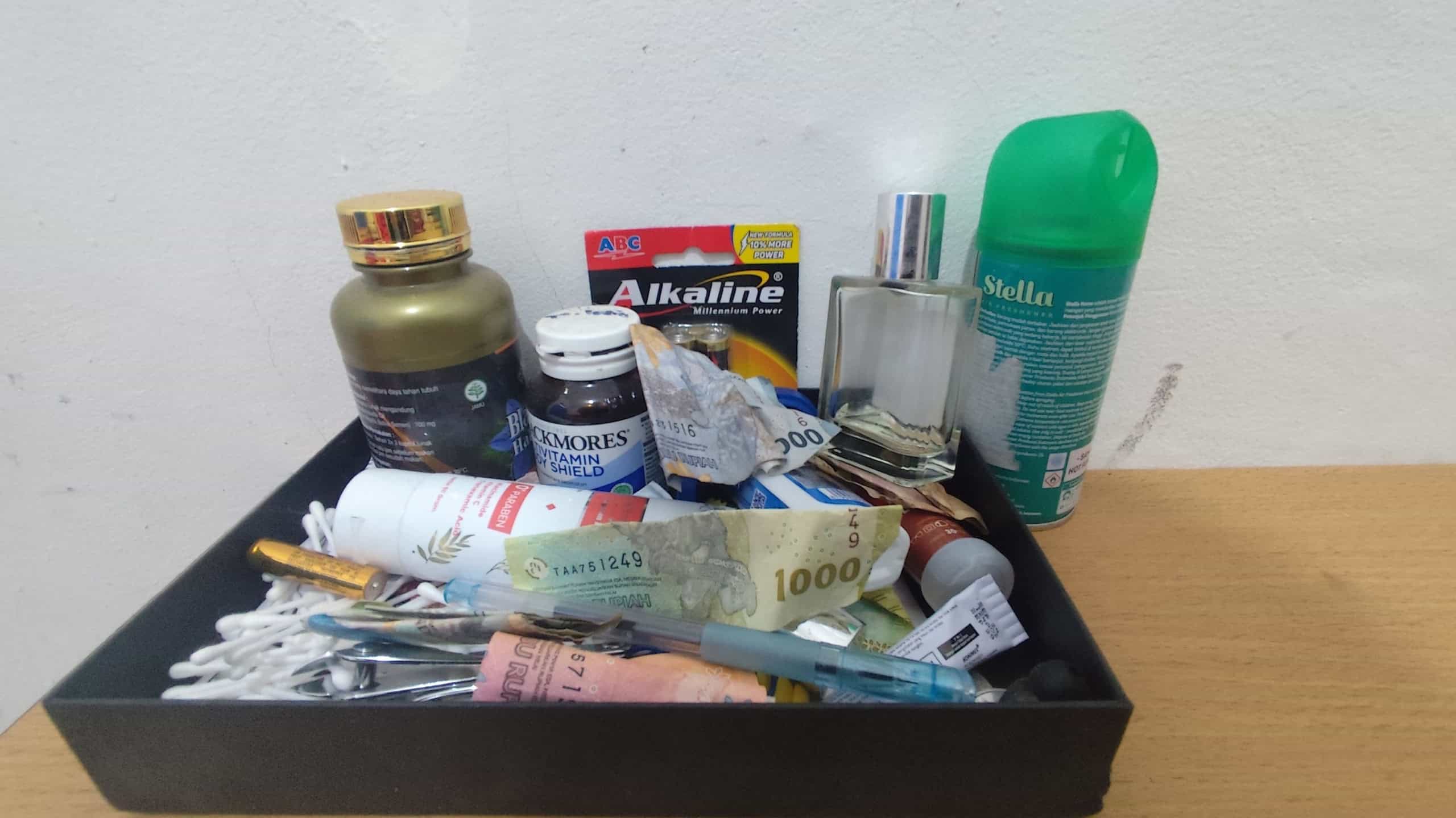 A messy yet realistic tray containing random household items, showcasing daily life chaos and habits.