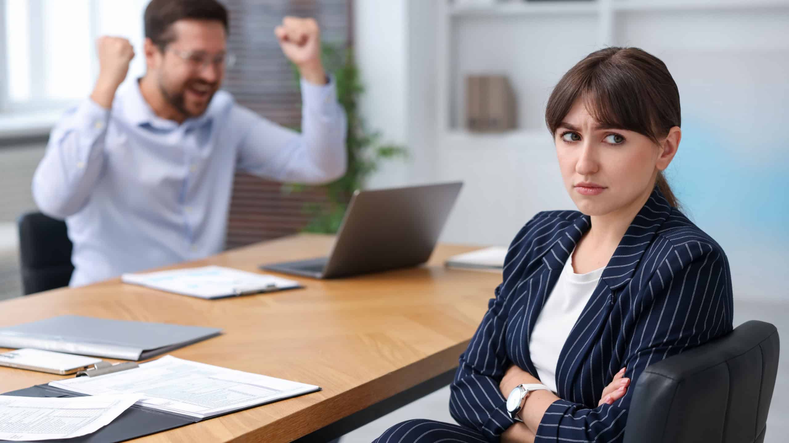 Woman feeling jealous of her colleague's success in office, selective focus